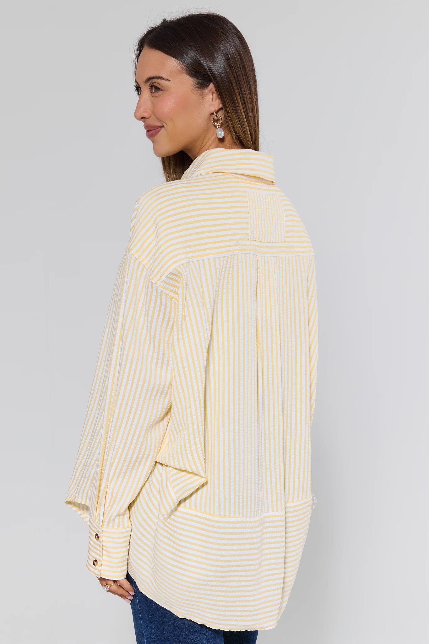 Woman wearing a yellow striped blazer against a gray background