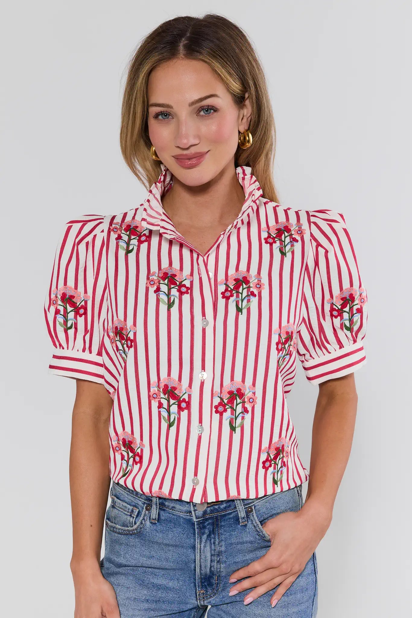 Woman wearing a red and white striped shirt with floral patterns on a plain background