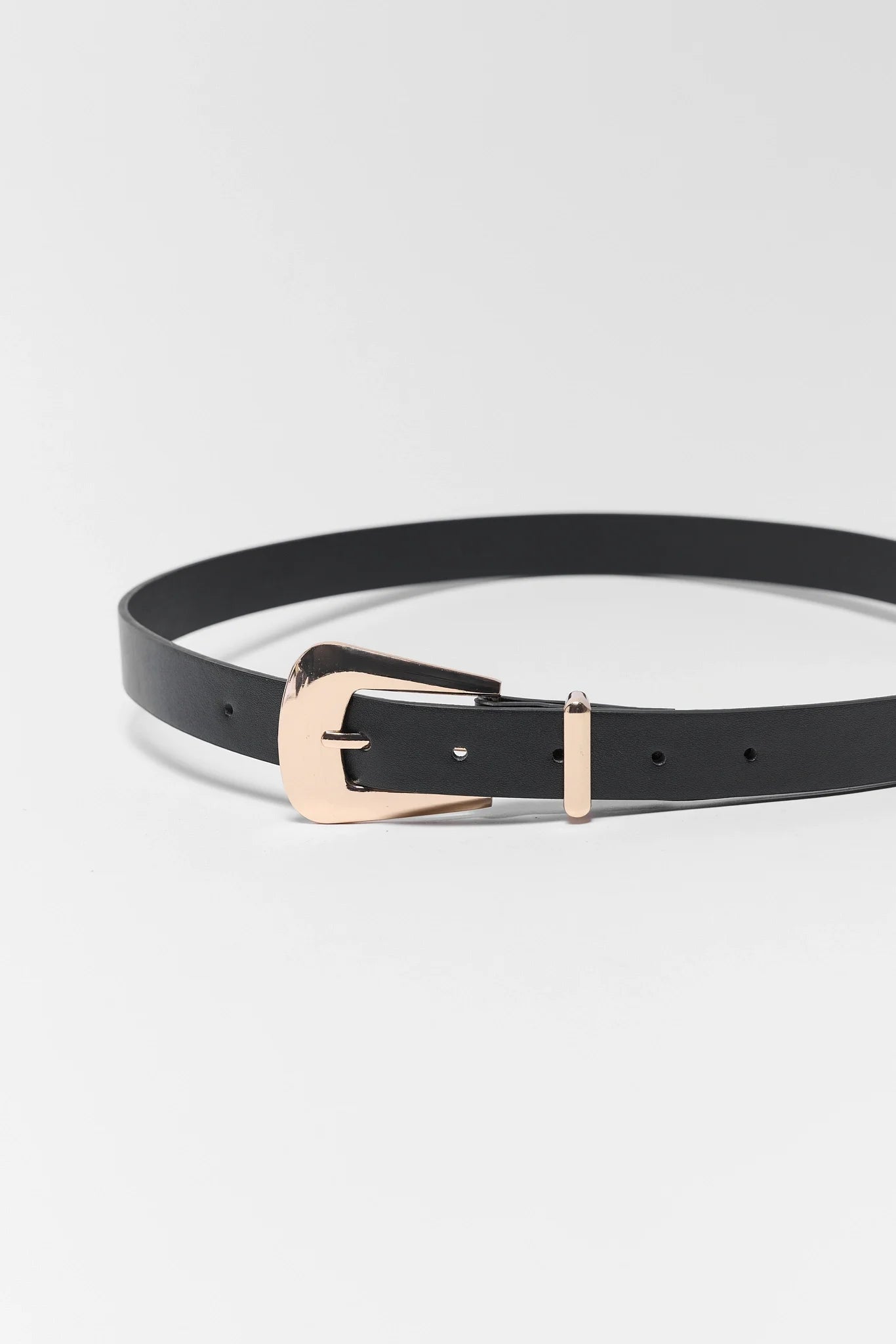 Black belt with a rose gold buckle on a light gray background