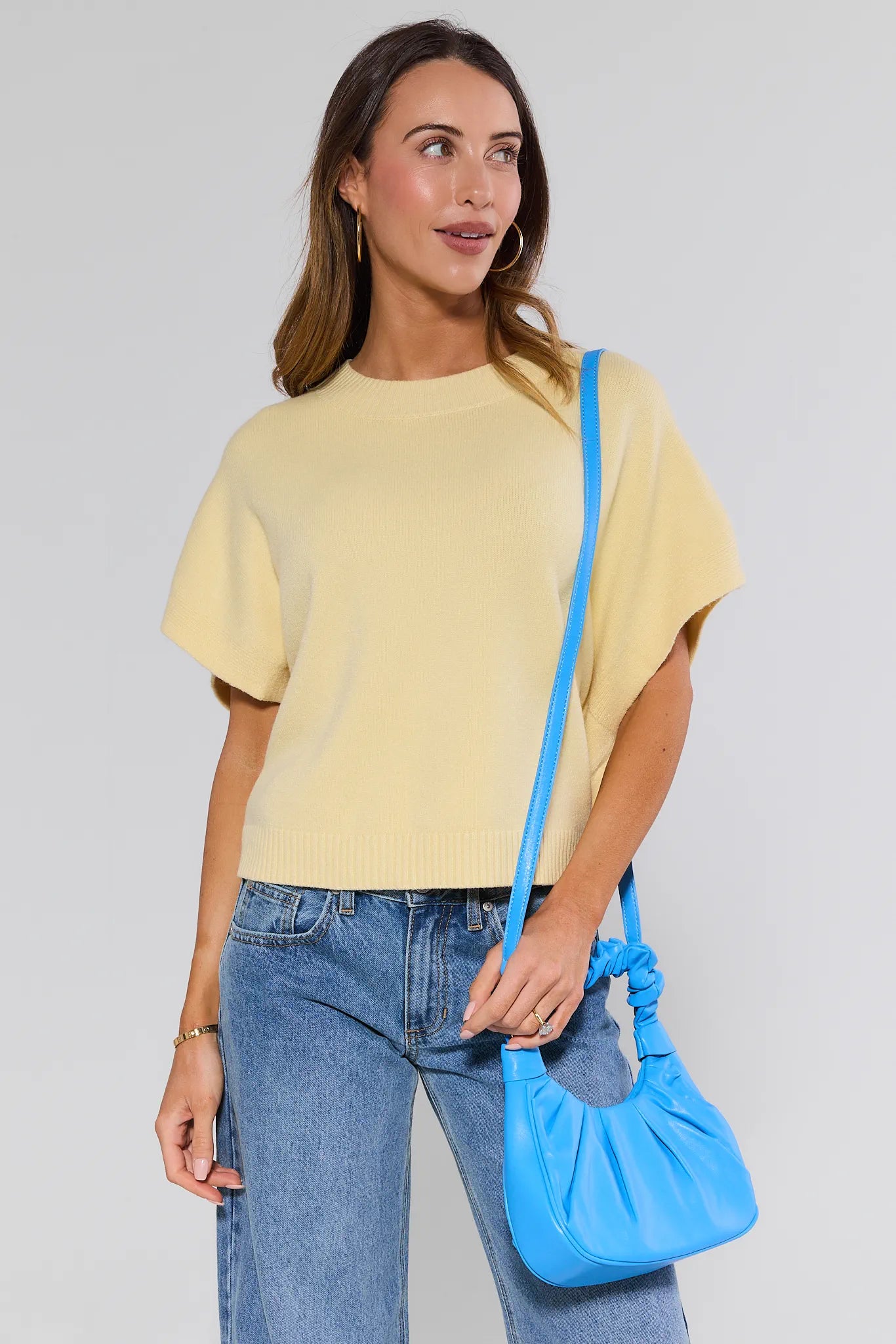 Woman holding a blue handbag against a plain background