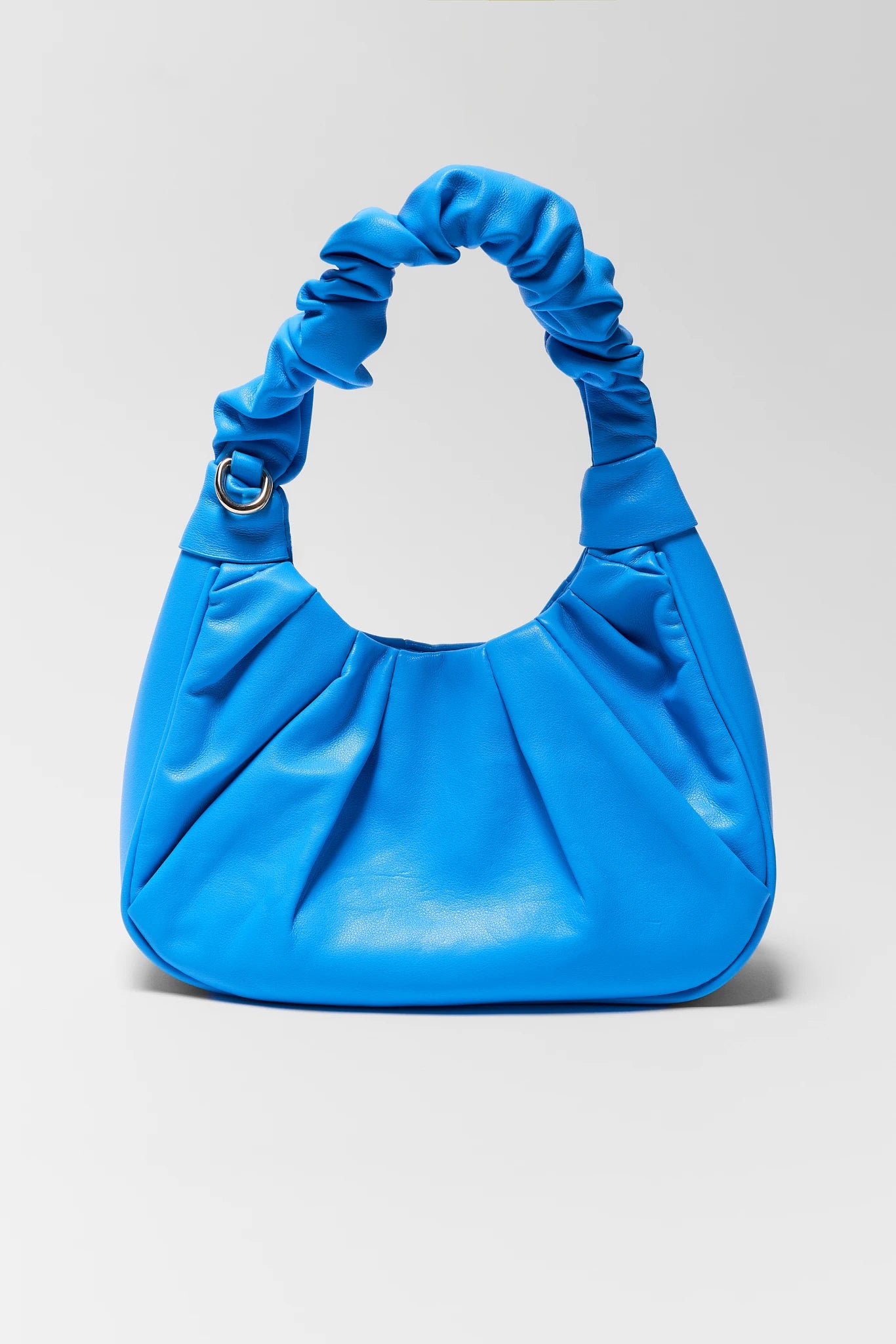 Blue handbag with ruched handle on a light gray background