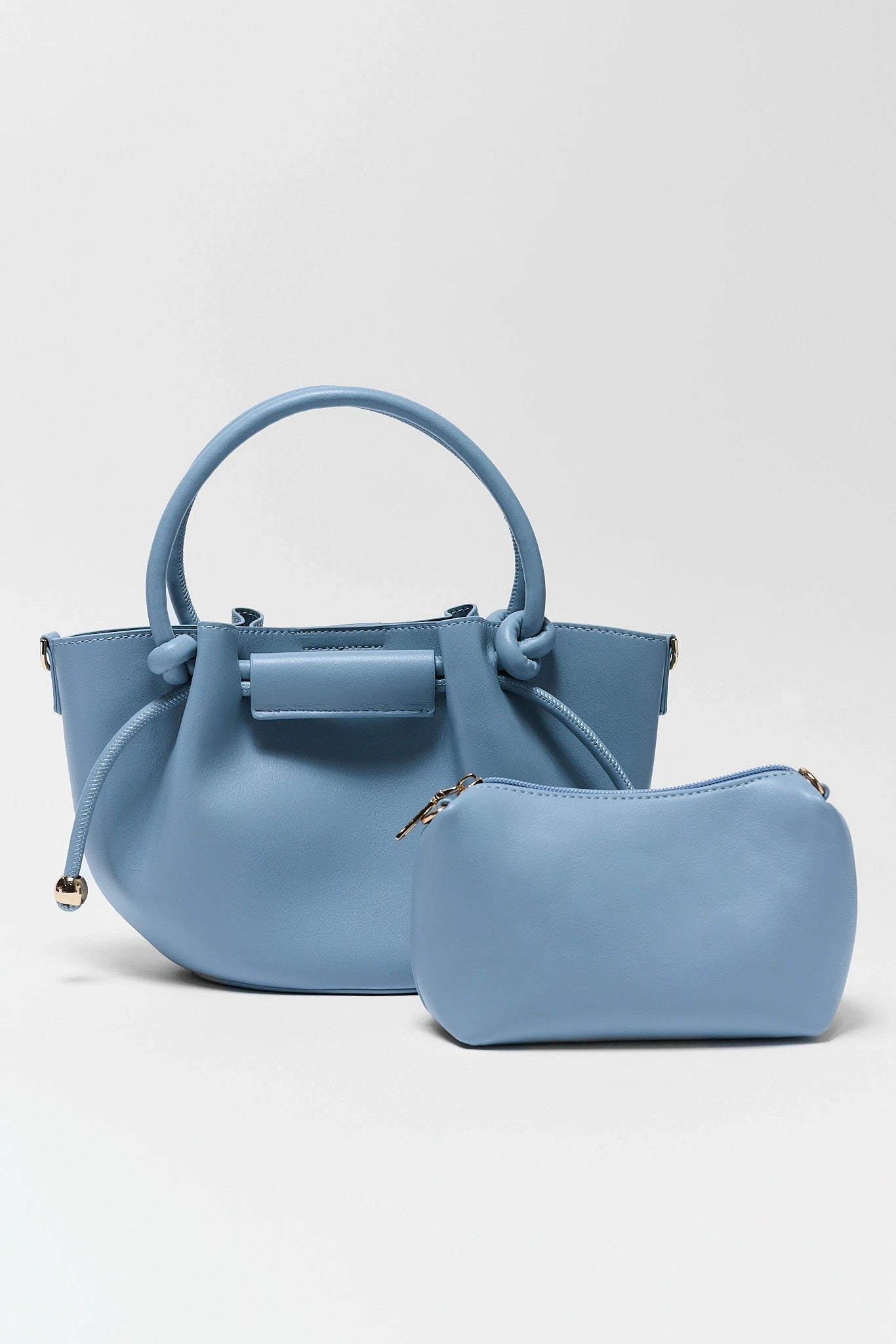 Blue handbag with matching pouch on a light gray background