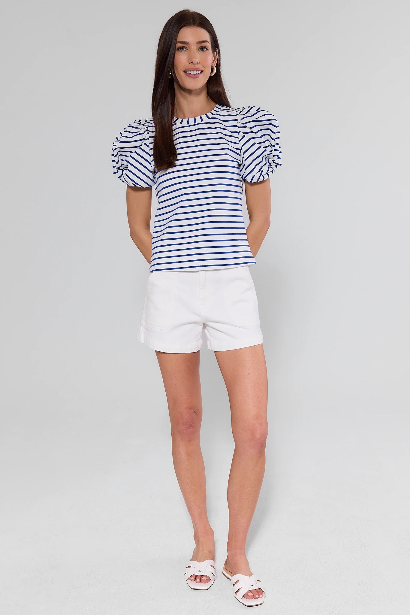 Woman wearing a blue and white striped top and shorts on a gray background