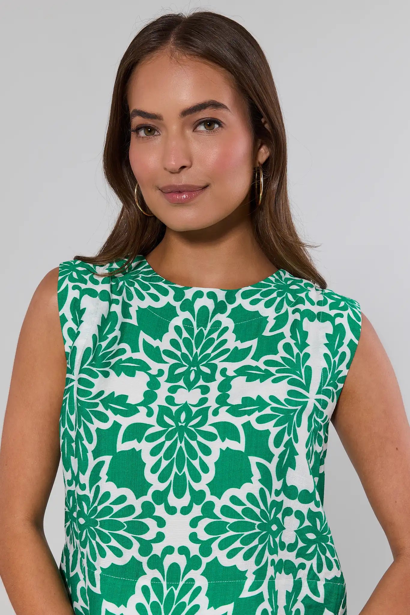 close up Woman wearing a green and white patterned sleeveless top against a plain background