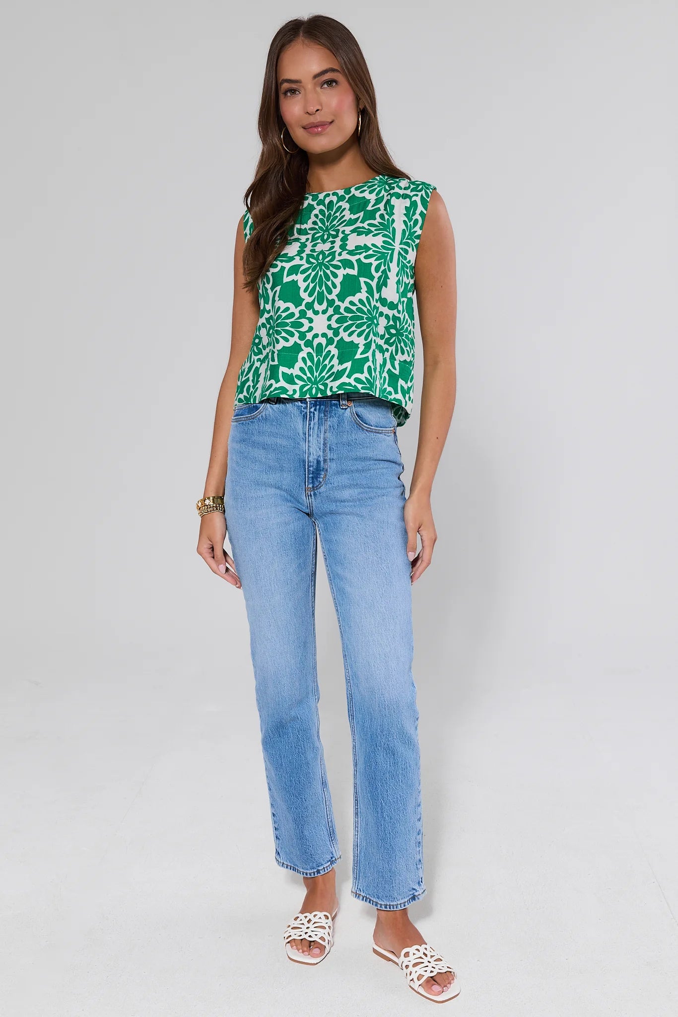 Woman wearing a green floral top and blue jeans on a white background