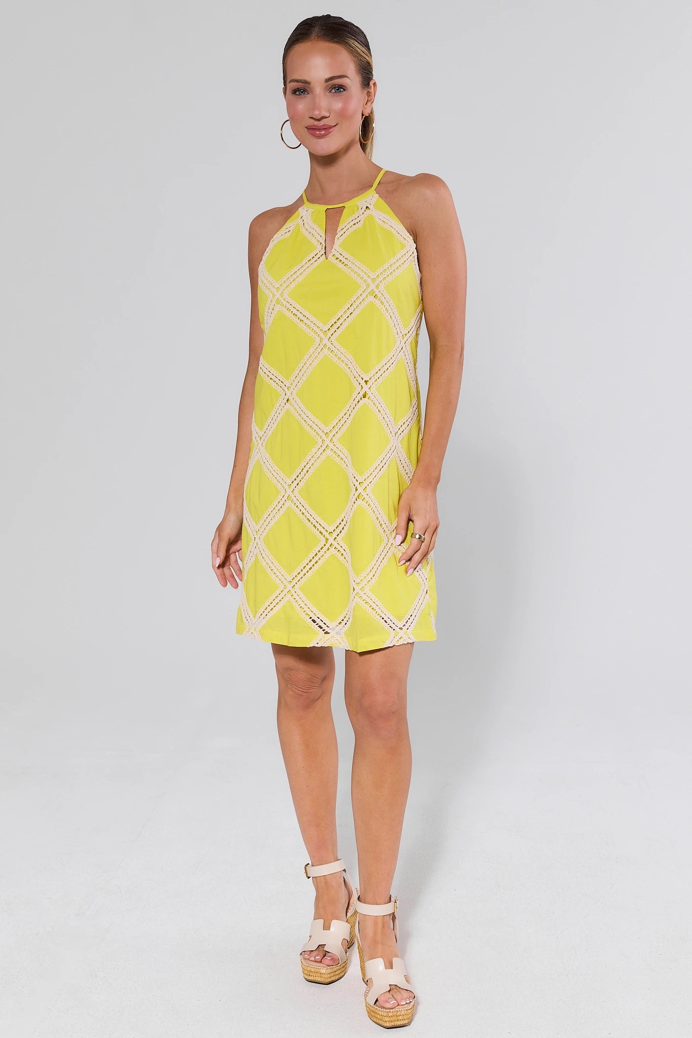 Woman wearing a yellow patterned dress and heels on a white background