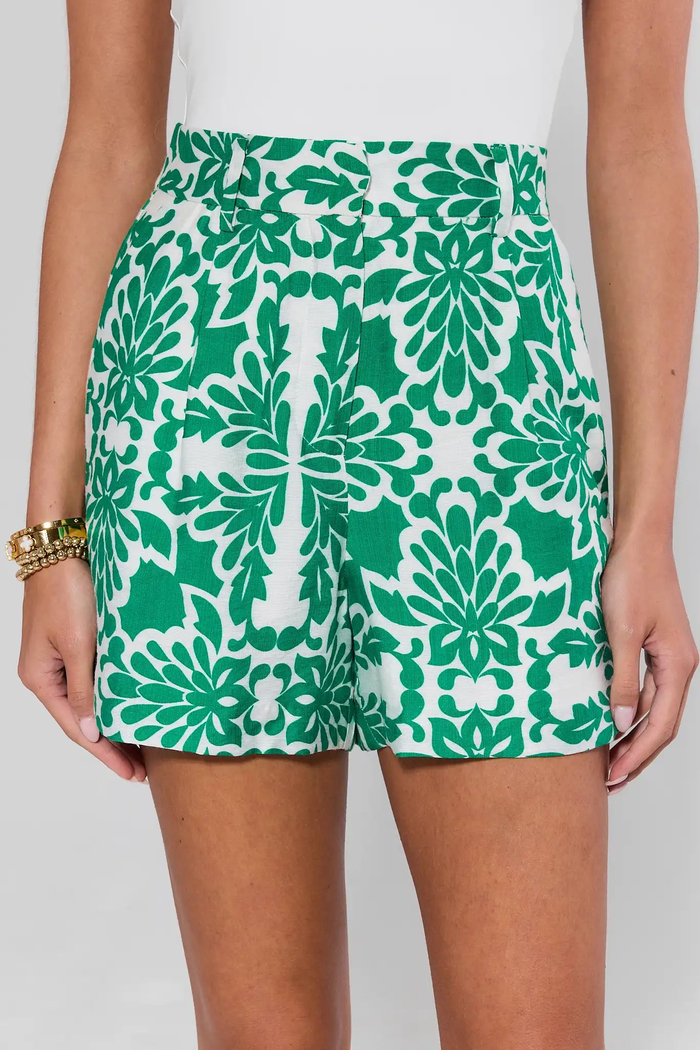 Green and white patterned shorts worn by a person on a plain background