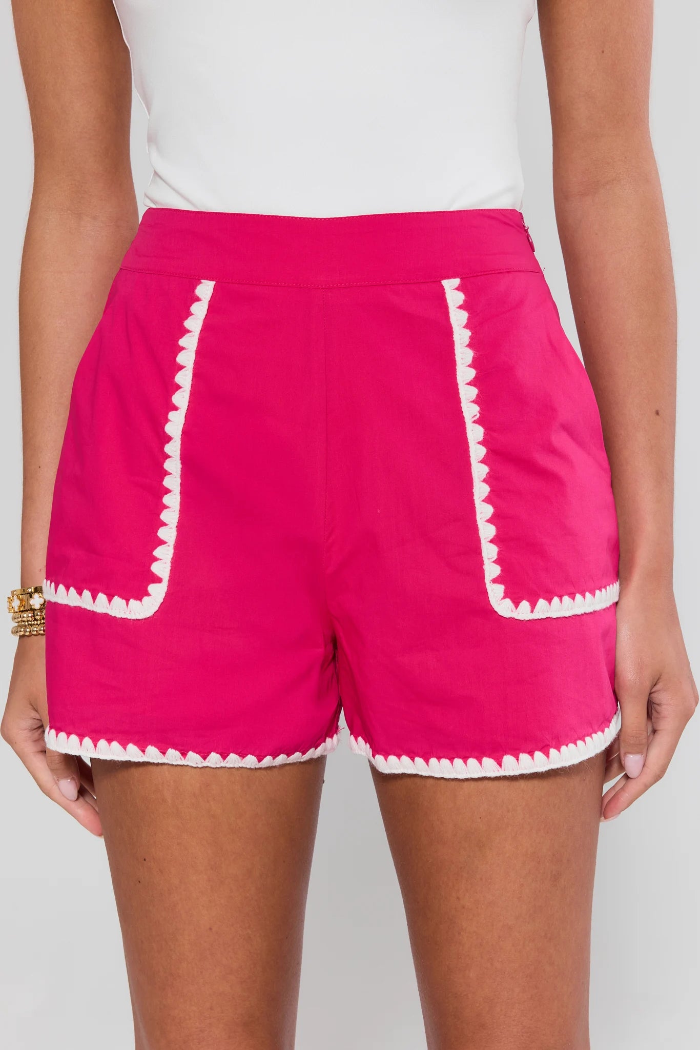 Person wearing bright pink shorts with white trim on a plain background