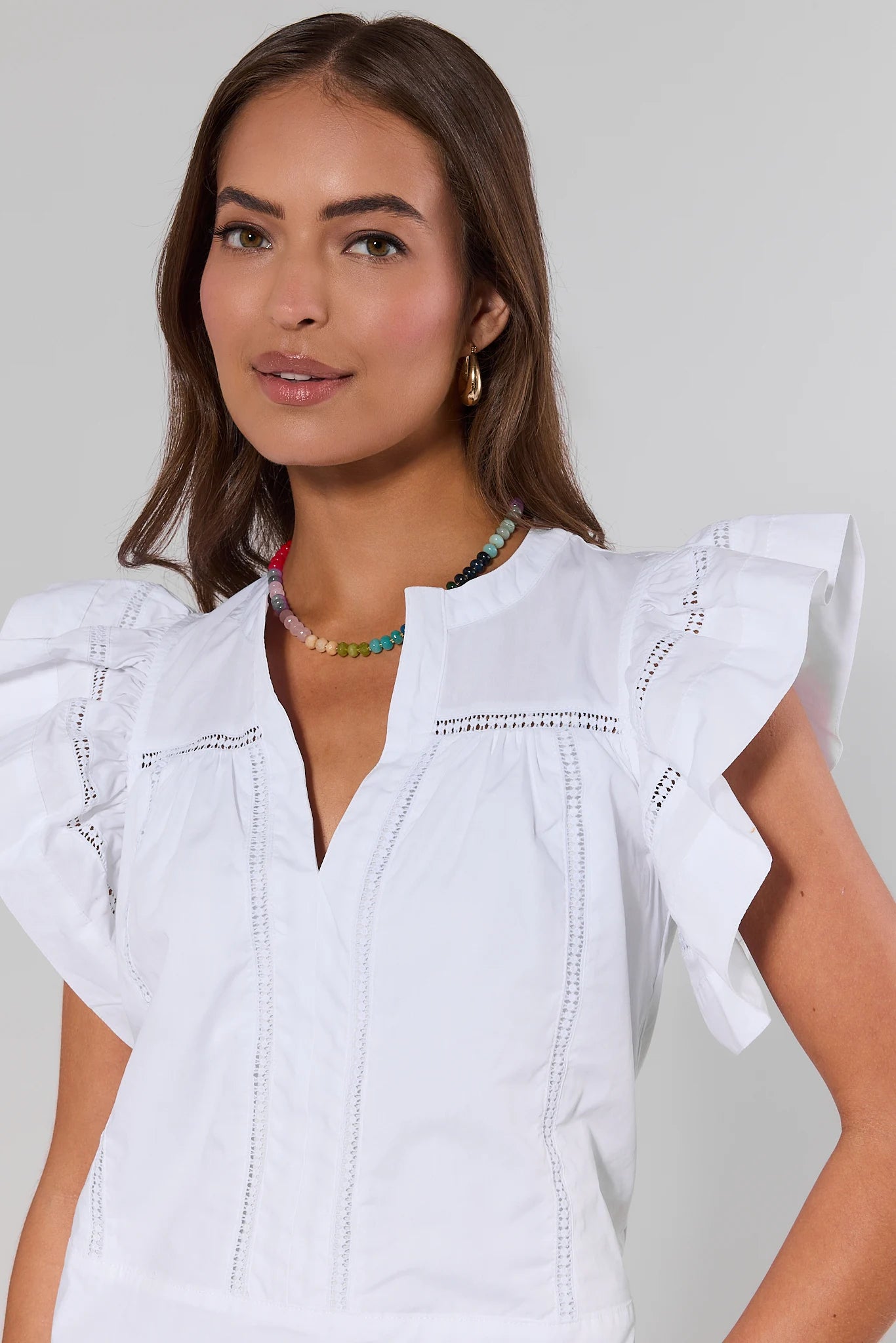 close up Woman wearing a white blouse with ruffled sleeves against a plain background