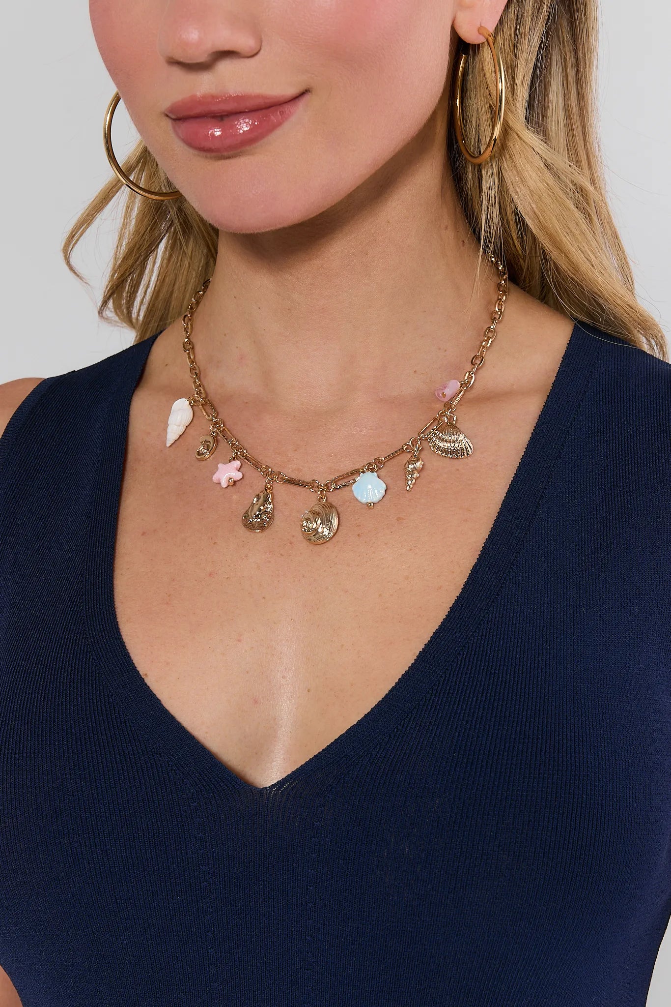 Necklace with various charms worn by a person against a neutral background