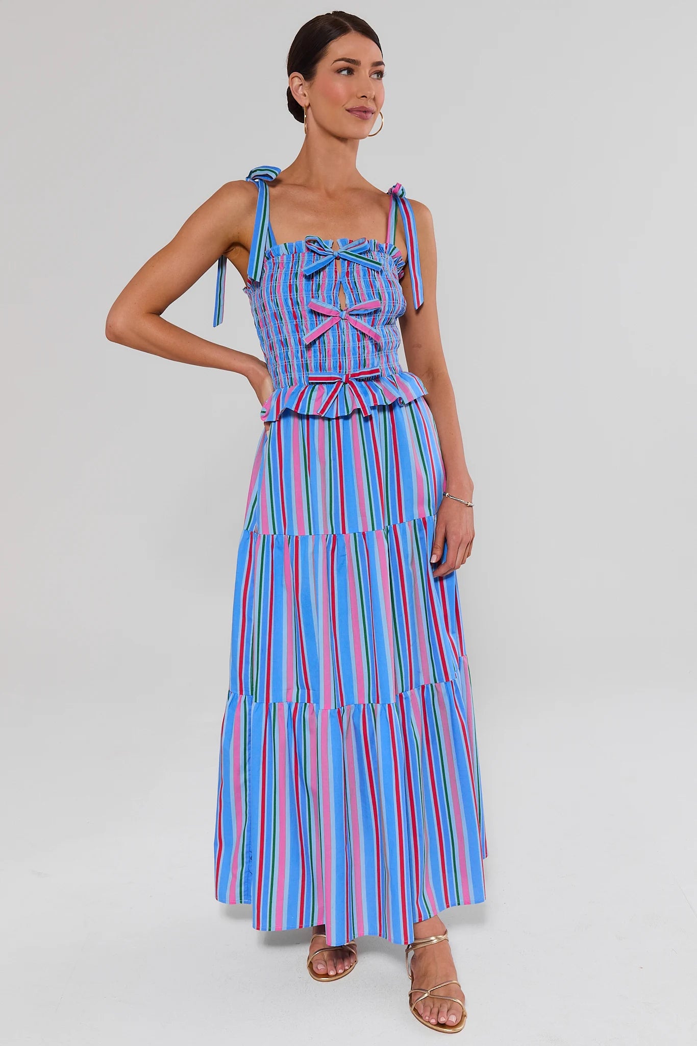 full body Woman wearing a colorful striped dress against a gray background
