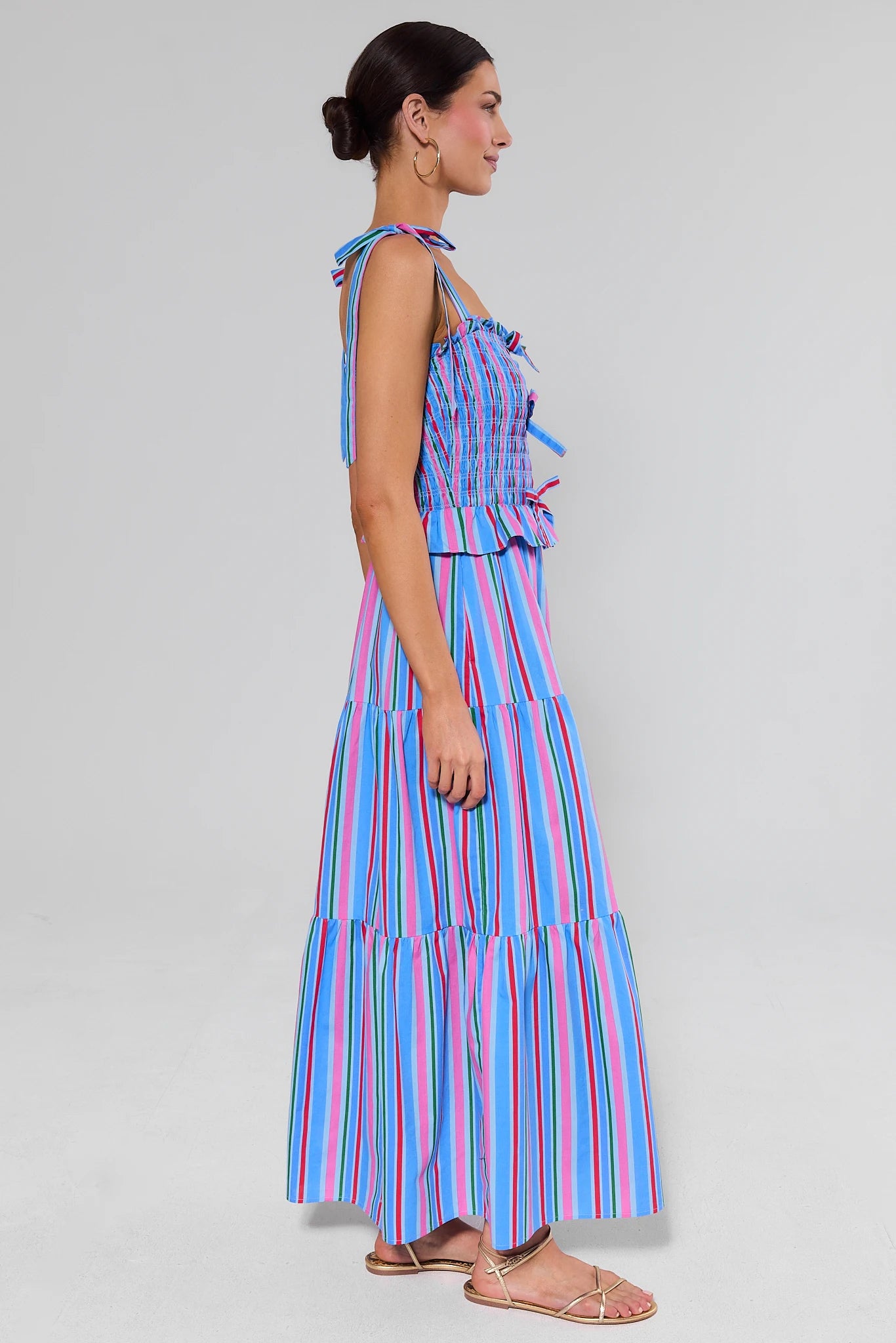 Woman wearing a colorful striped margot dress on a plain background