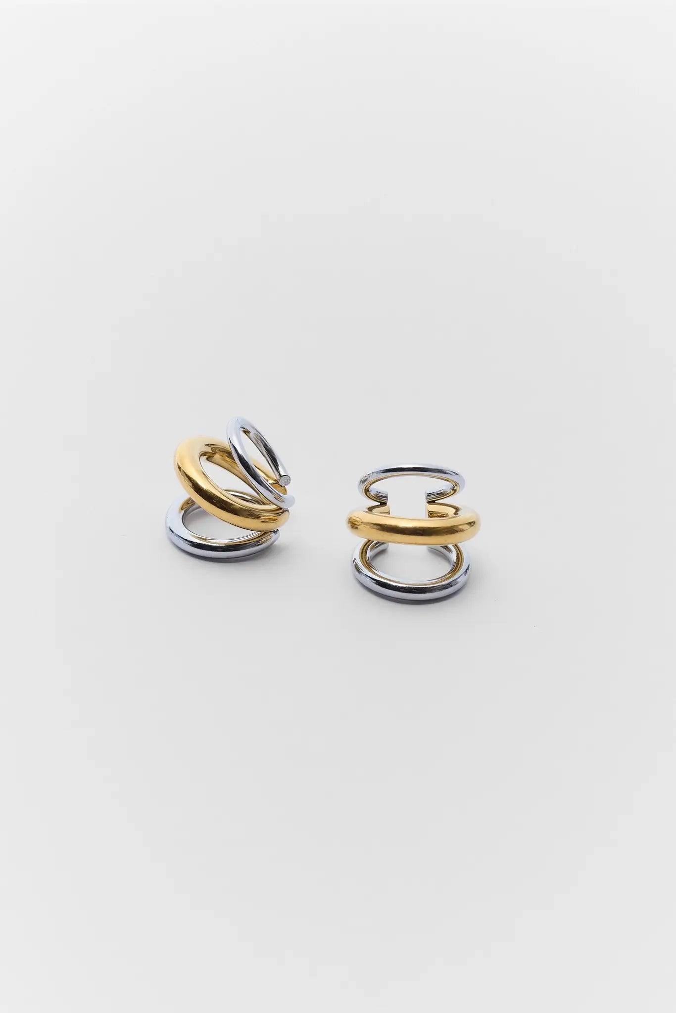 Pair of gold and silver ring earrings on a light gray background