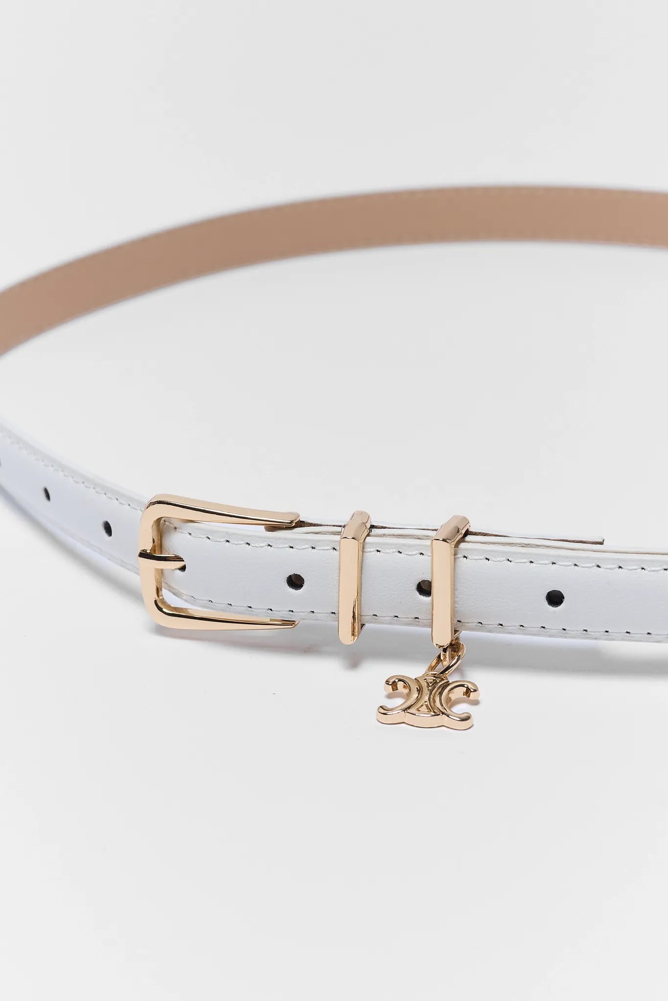 White belt with gold buckle and charm on a white background