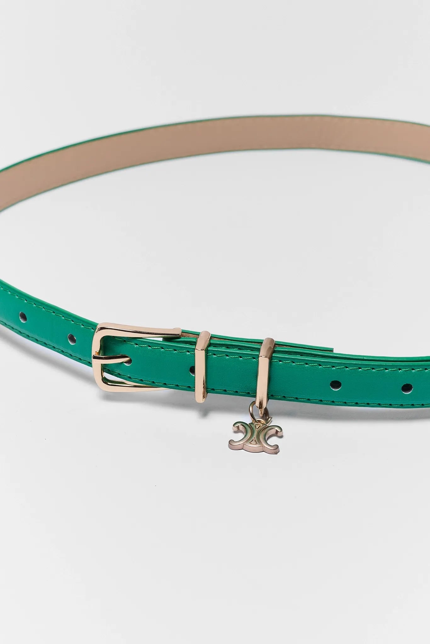 Green belt with a gold buckle and charm on a white background