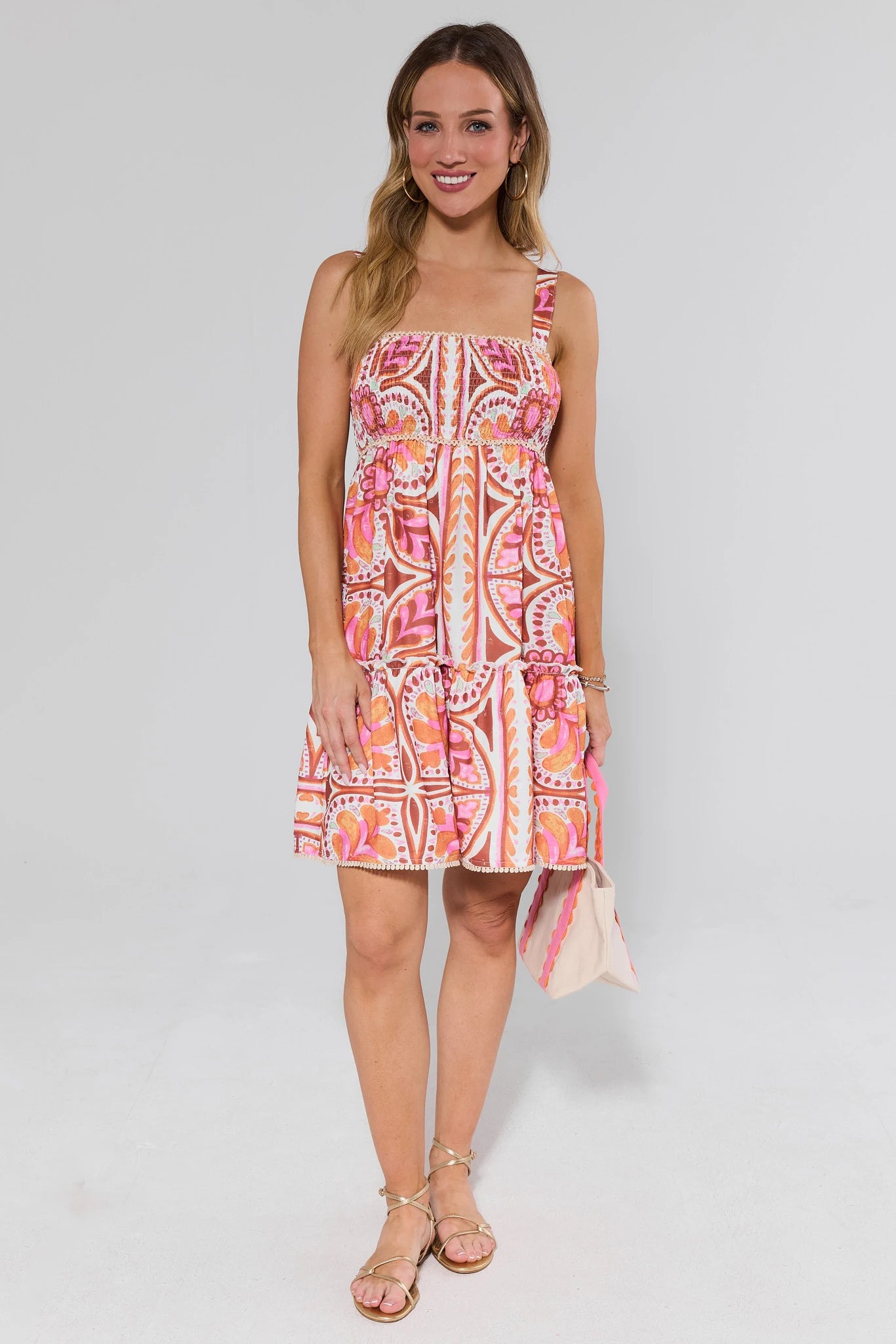 Woman wearing a colorful patterned dress and sandals on a white background