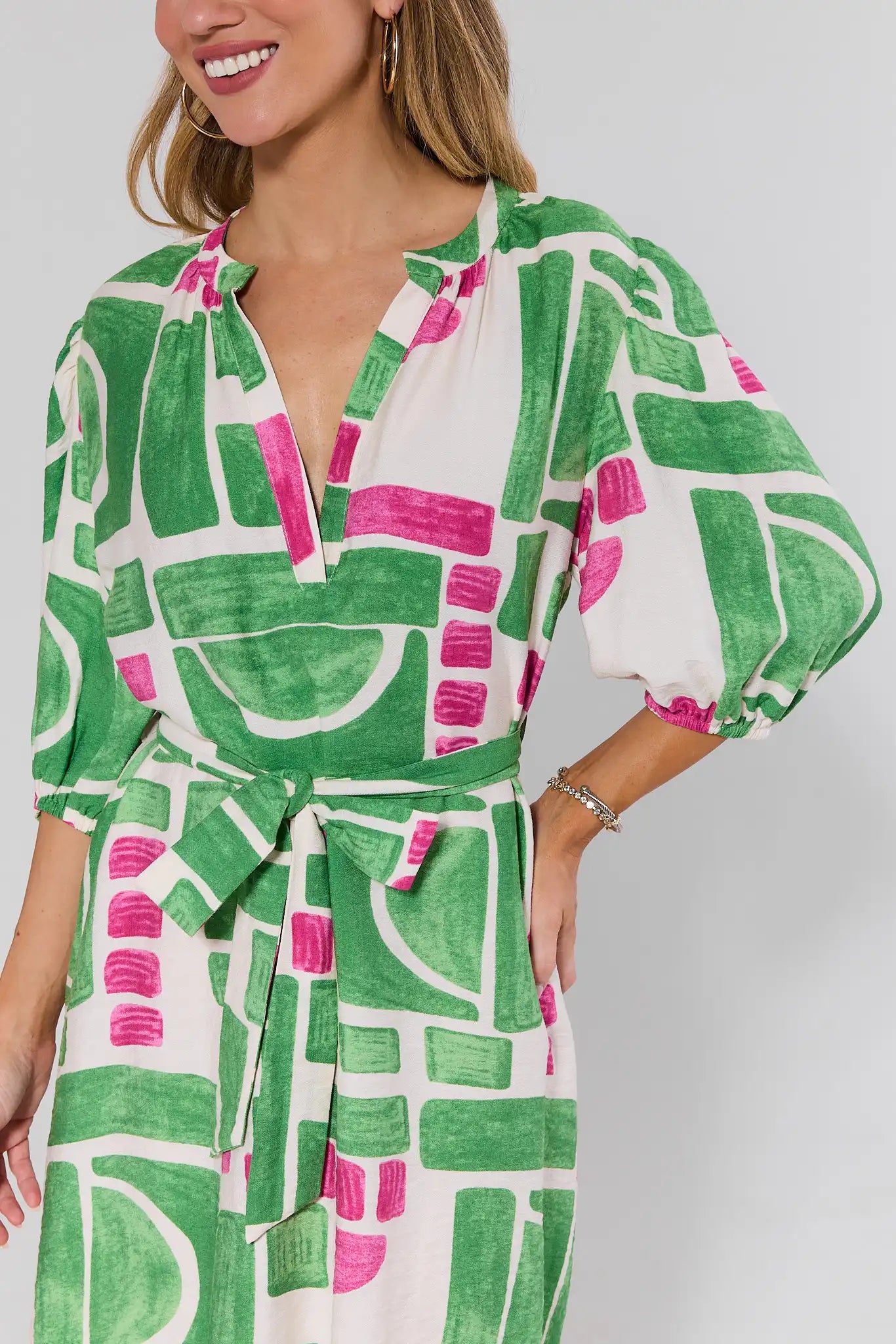 close up Woman wearing a green and pink patterned dress on a plain background