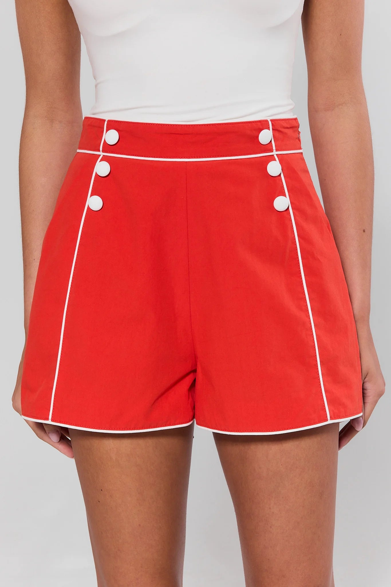Red shorts with white buttons and trim on a plain background