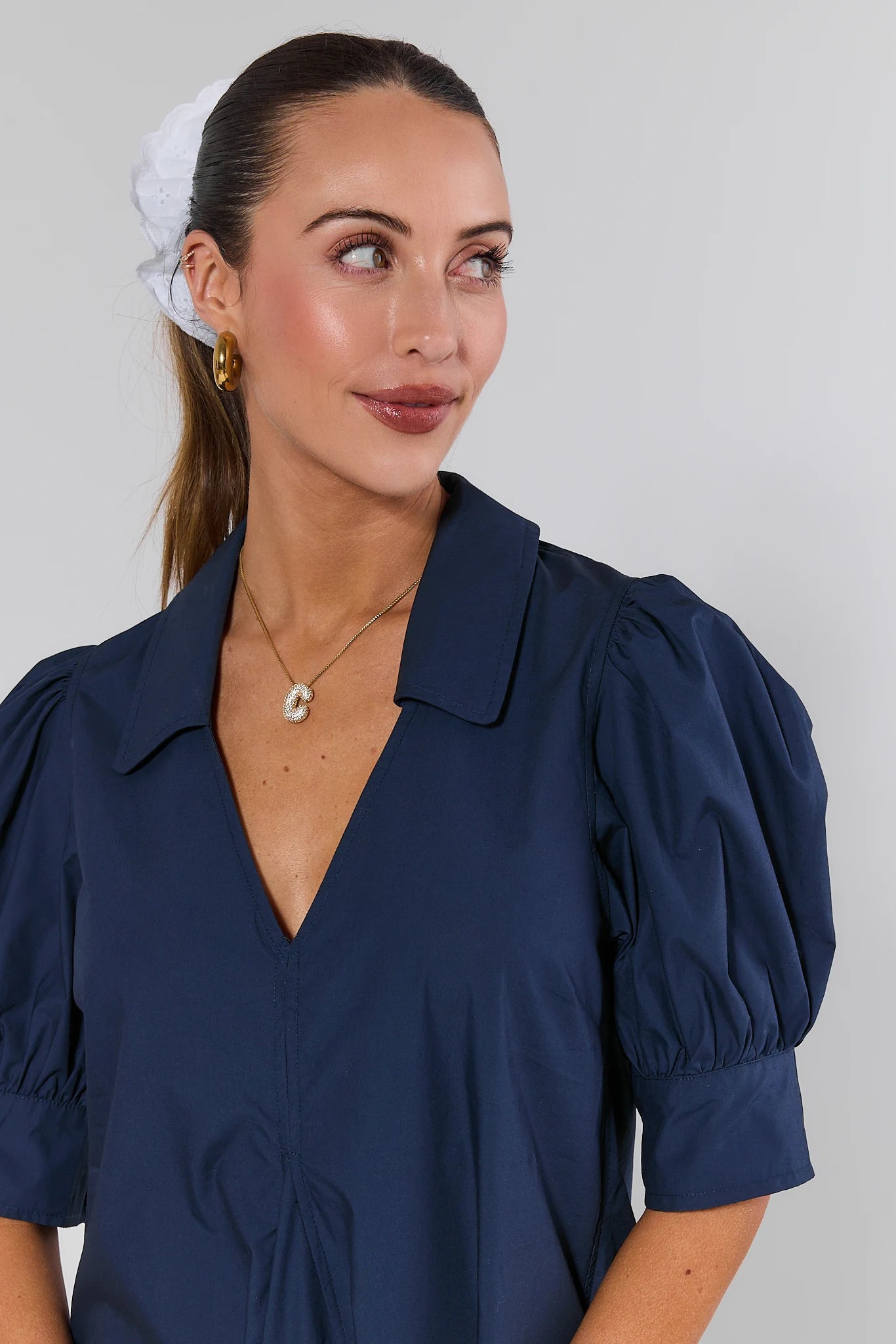 Woman wearing a navy blue blouse with puffed sleeves against a plain background