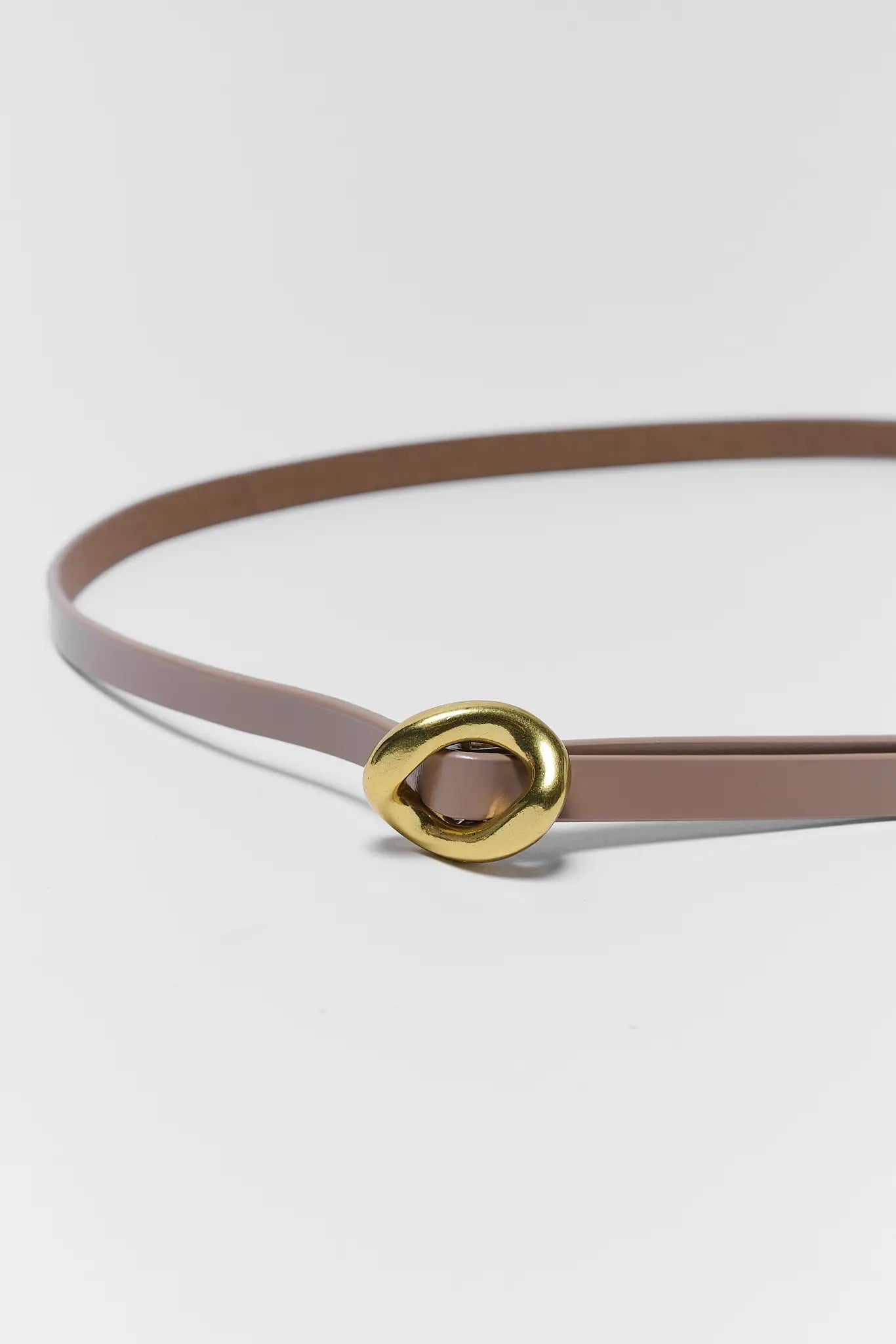 Thin brown belt with a gold buckle on a light gray background
