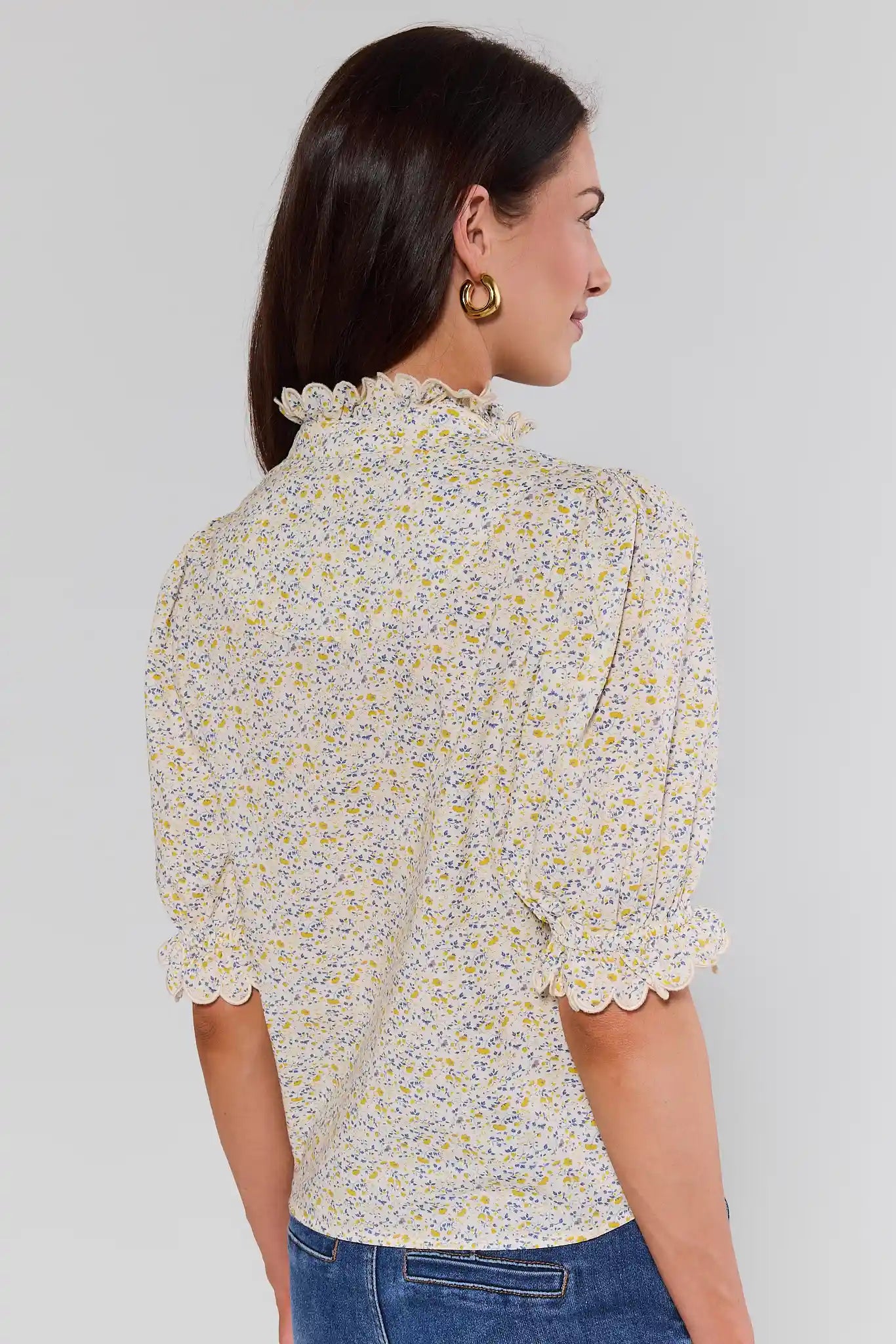 Woman standing wearing a floral blouse with a plain background