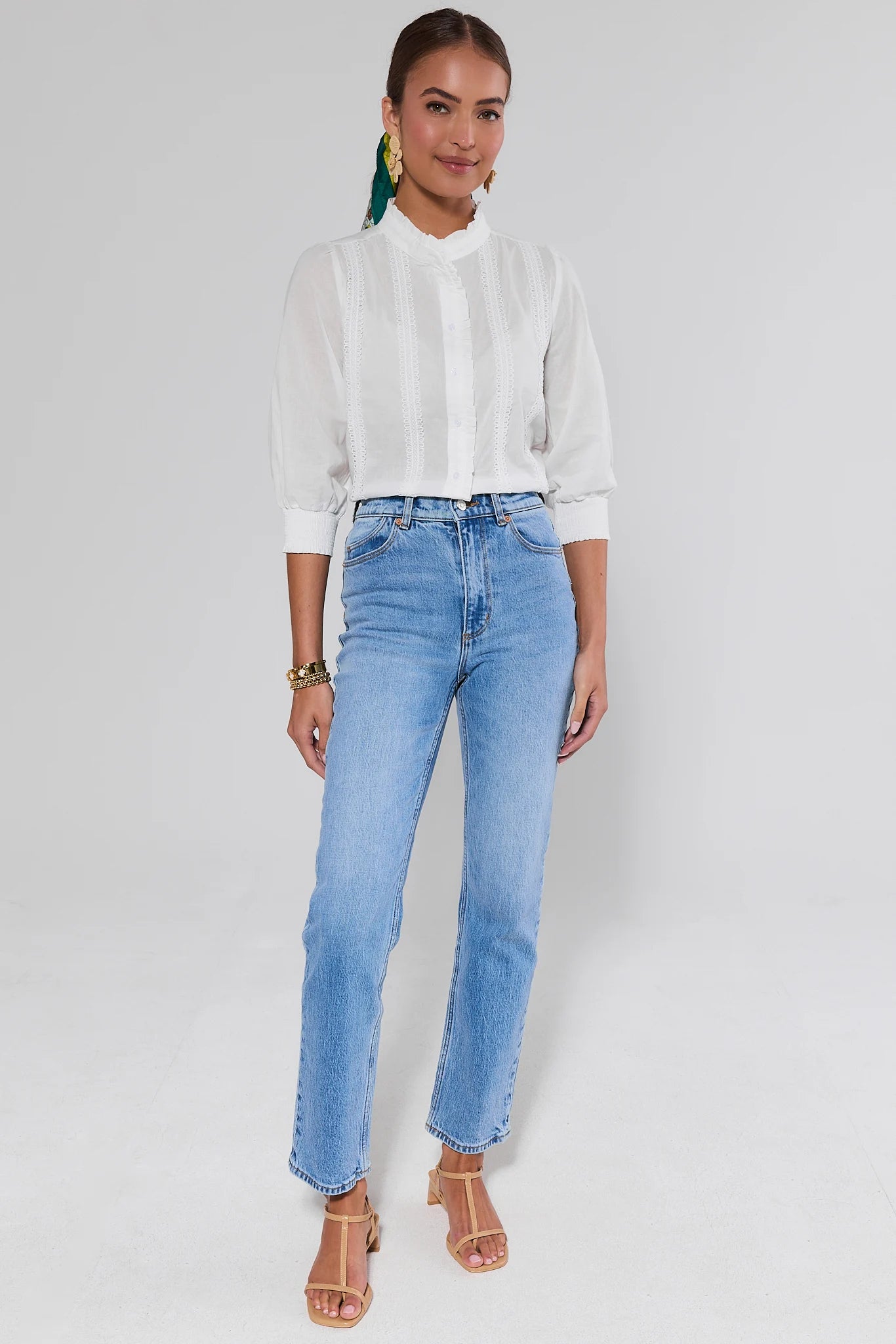 Woman wearing a white blouse and light blue jeans on a plain background
