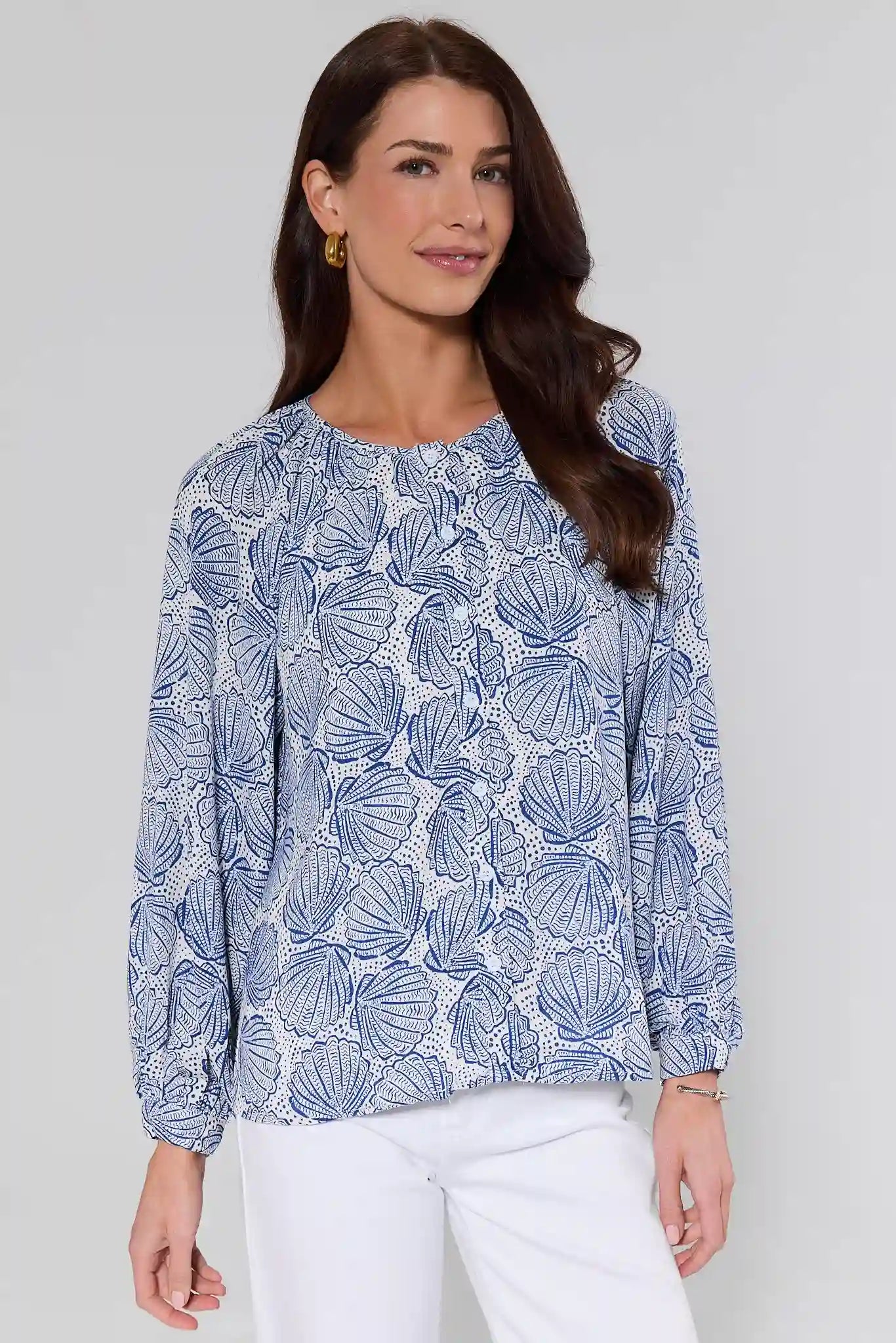 Woman wearing a blue shell patterned blouse against a white background