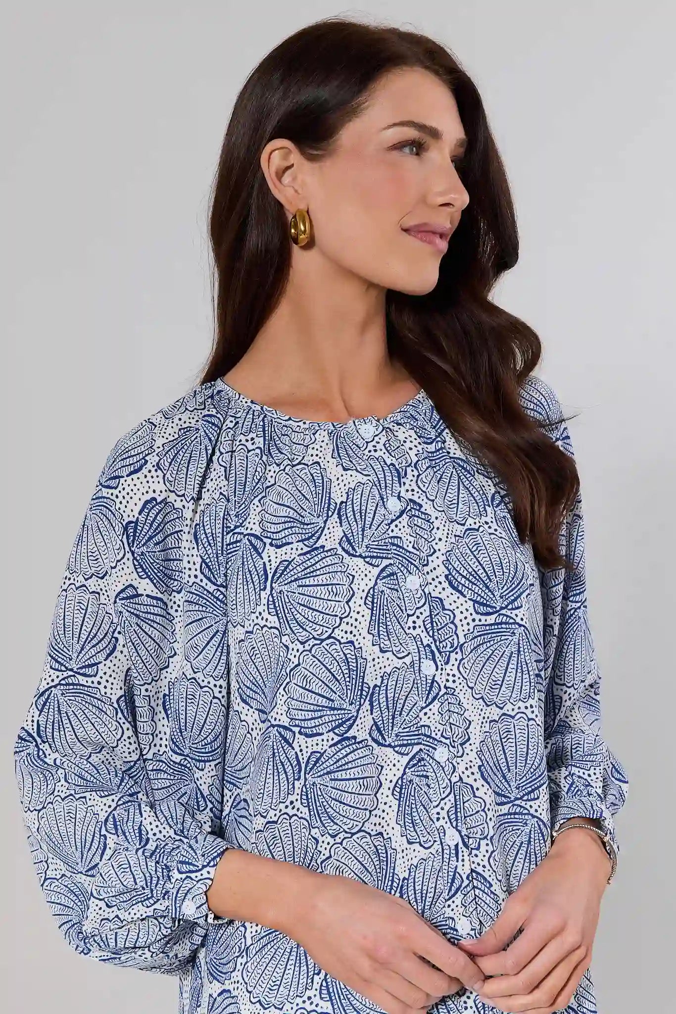 close up Woman wearing a blue patterned blouse against a gray background