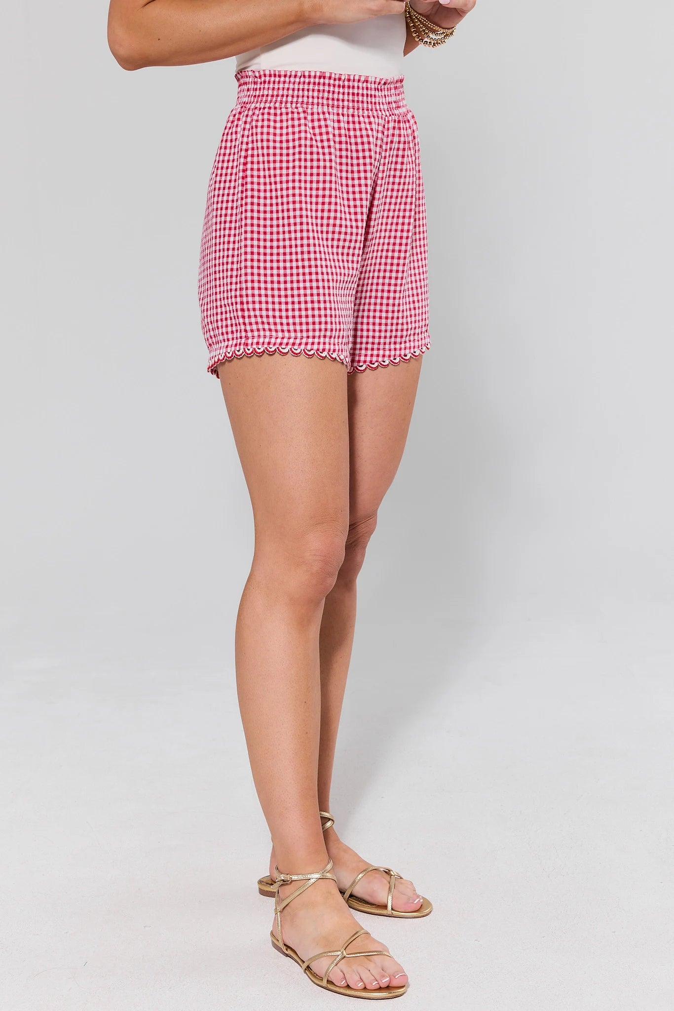 side shot Person wearing red and white checkered shorts on a plain background