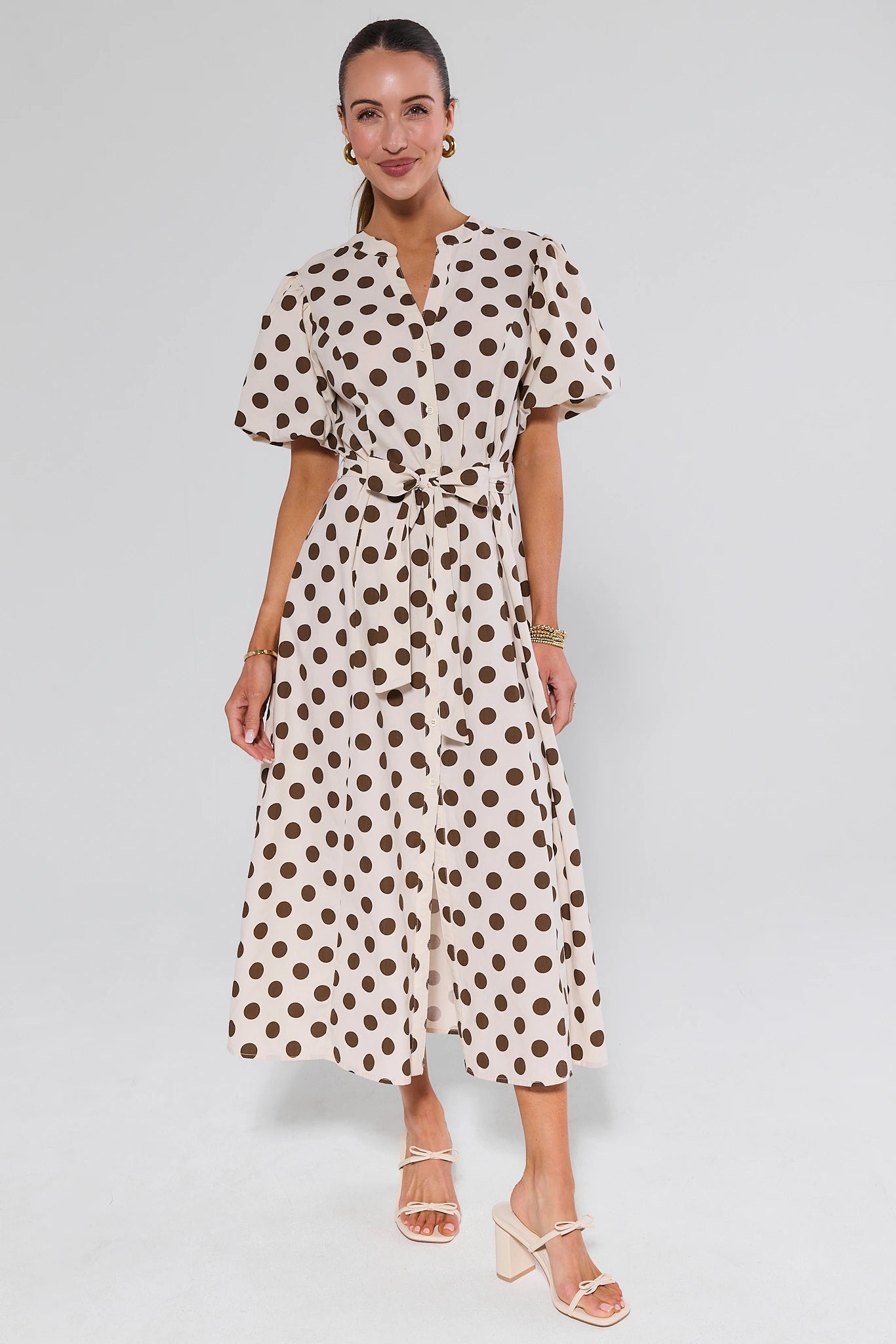 Woman wearing a polka dot dress on a plain background