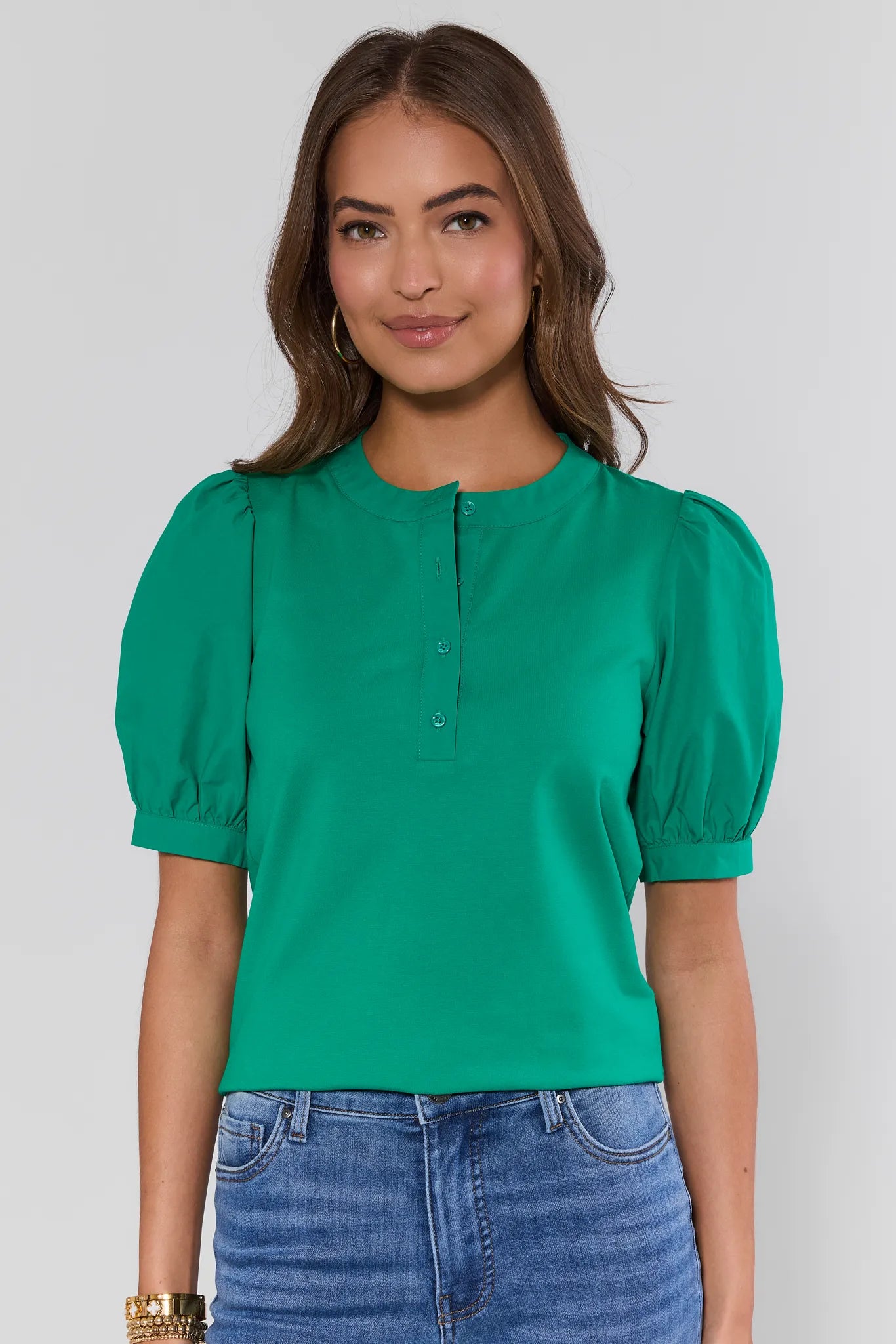 Woman wearing a green blouse with puffed sleeves against a plain background