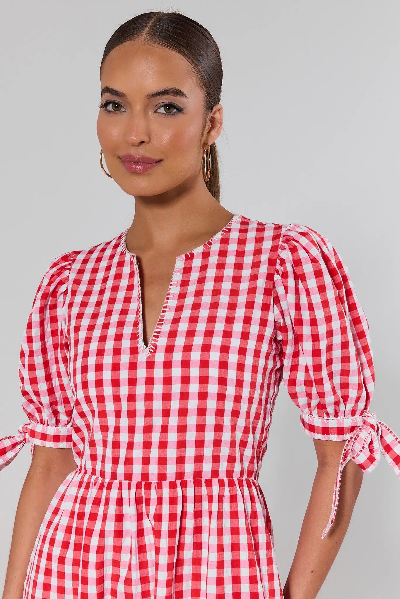 close up Woman wearing a red and white checkered dress against a plain background