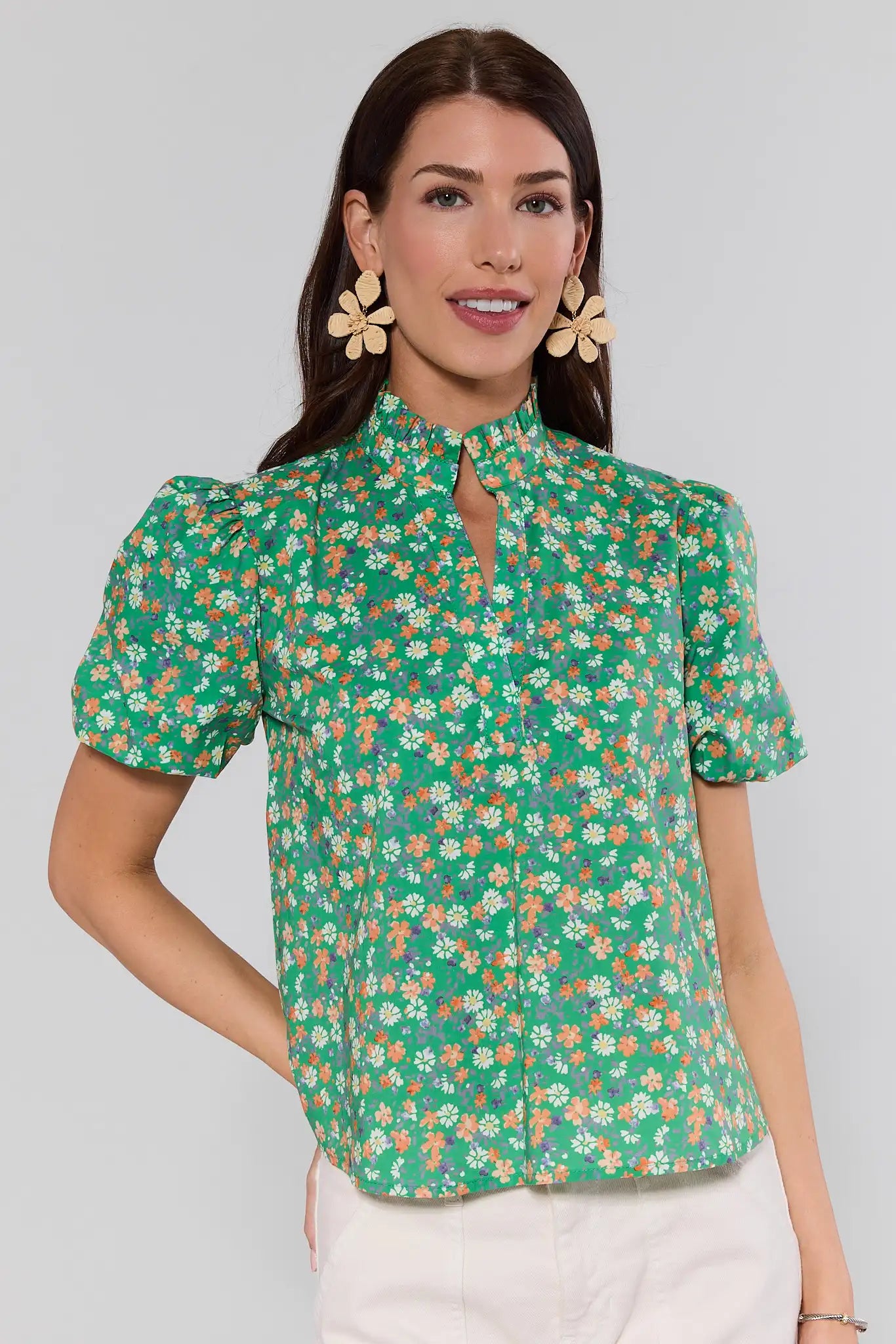 Woman wearing a green floral blouse against a gray background