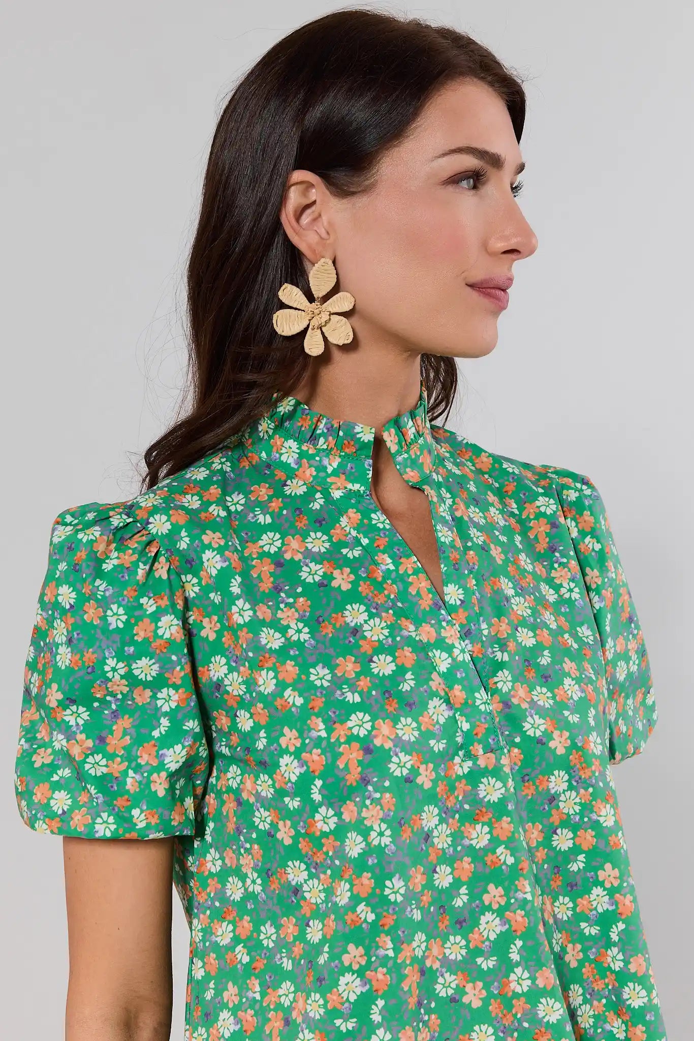 close up Woman wearing a green floral dress with puff sleeves against a plain background