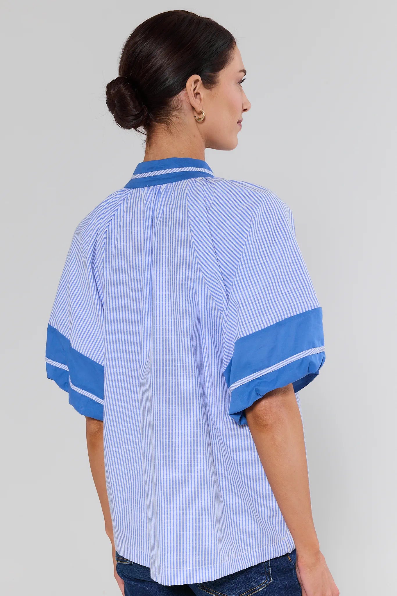Woman wearing a blue and white shirt with blue accents on a gray background