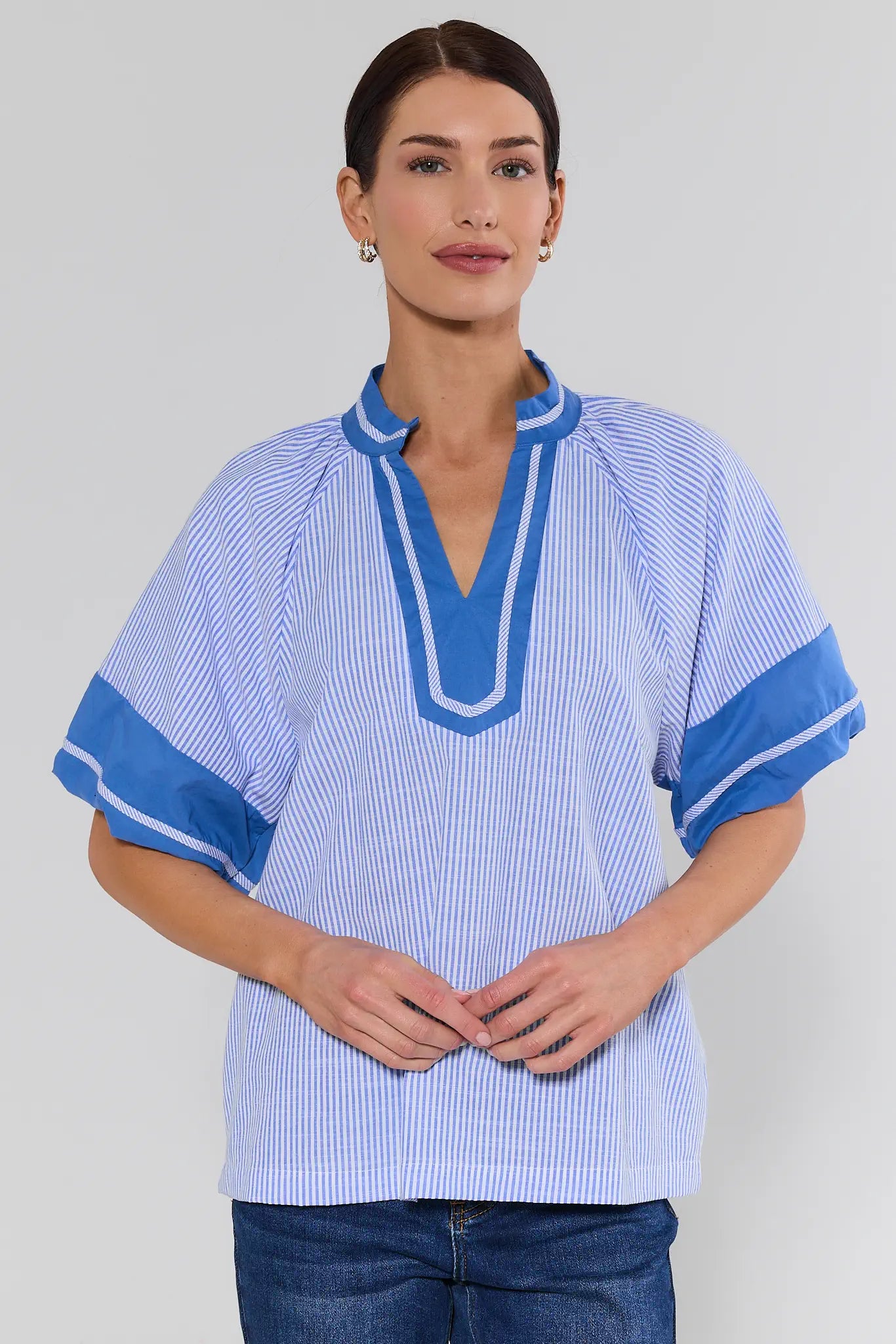 Woman wearing a blue striped shirt with a plain background