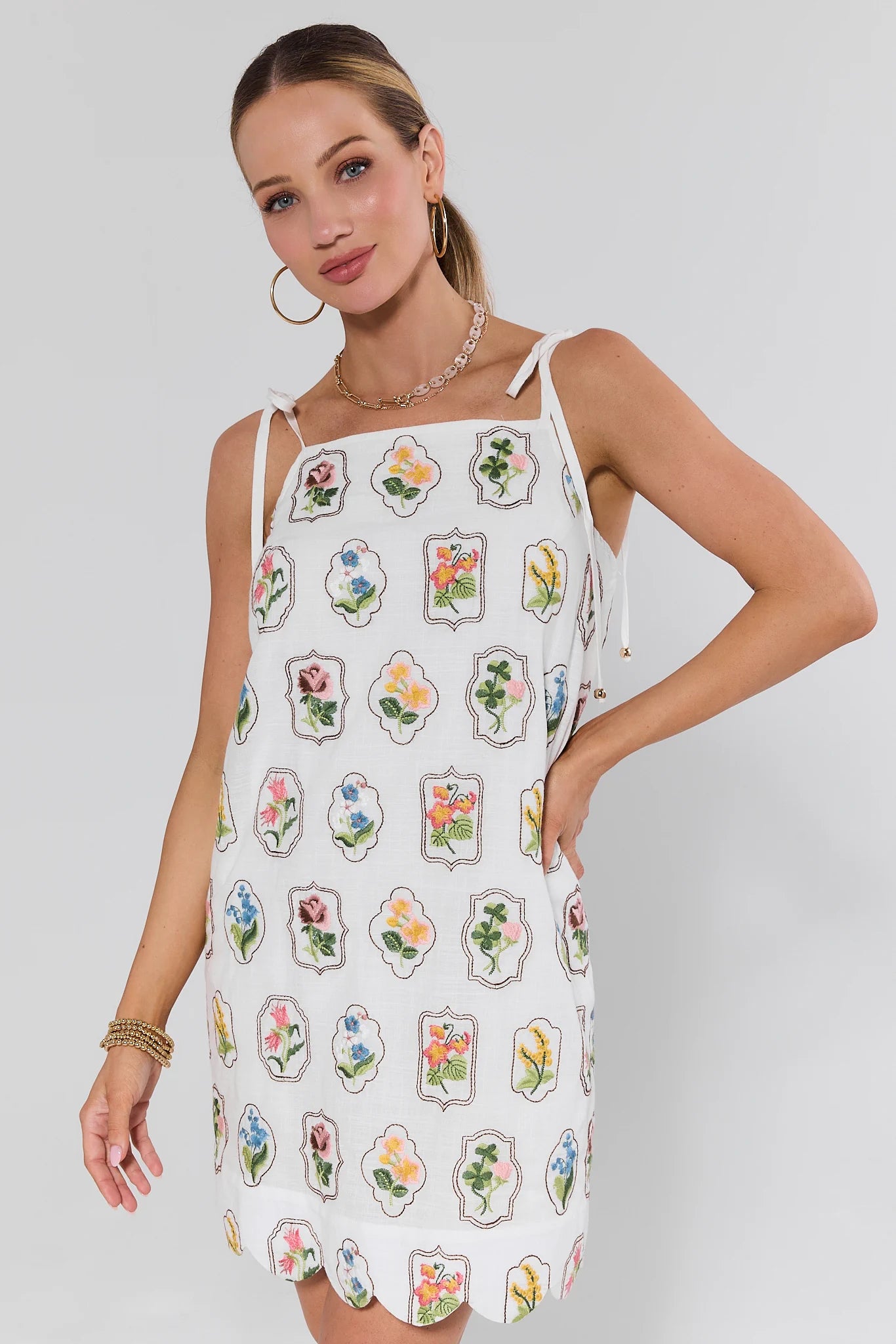 Woman wearing a white dress with floral patterns on a plain background