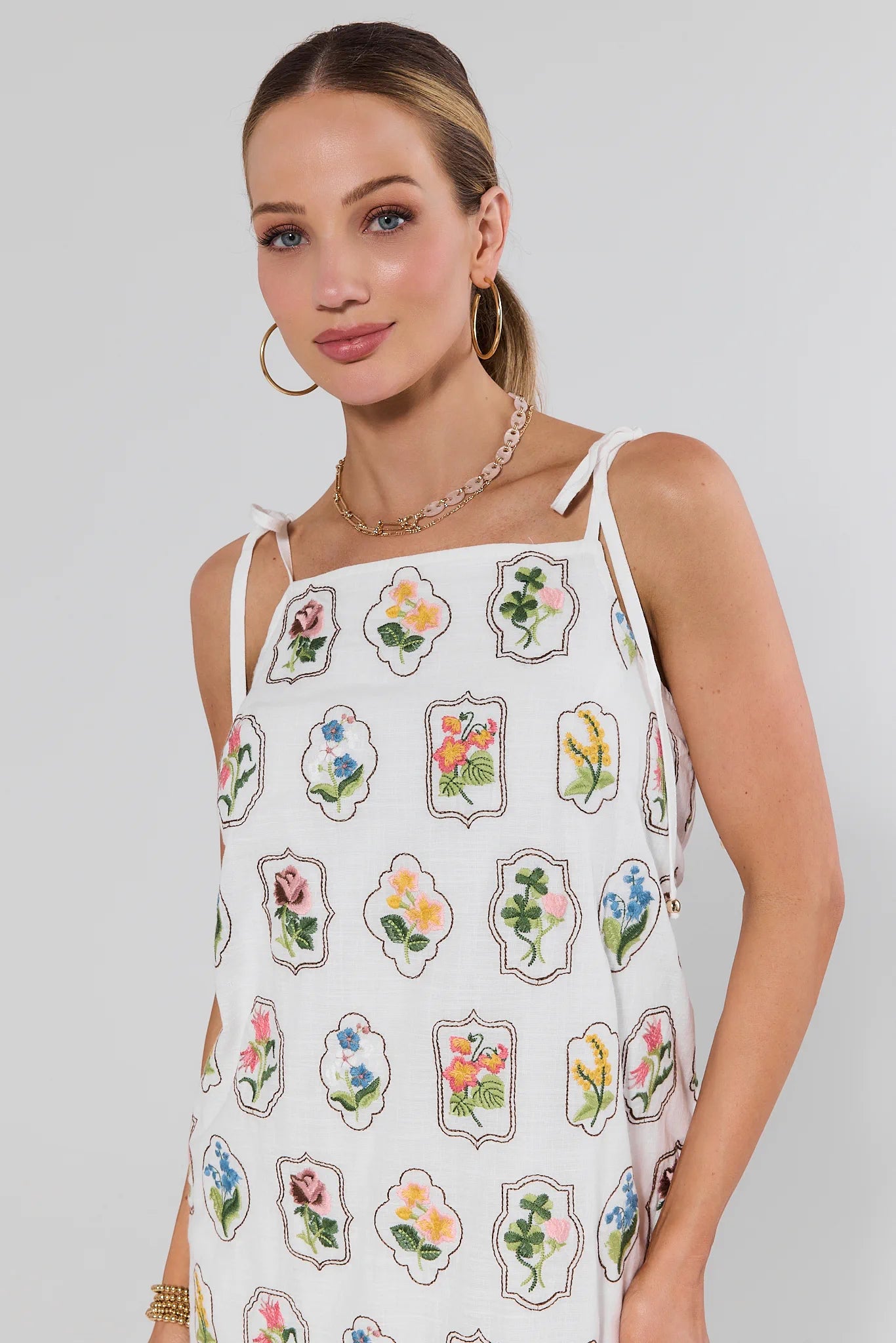 Woman wearing a white dress with floral patterns on a plain background