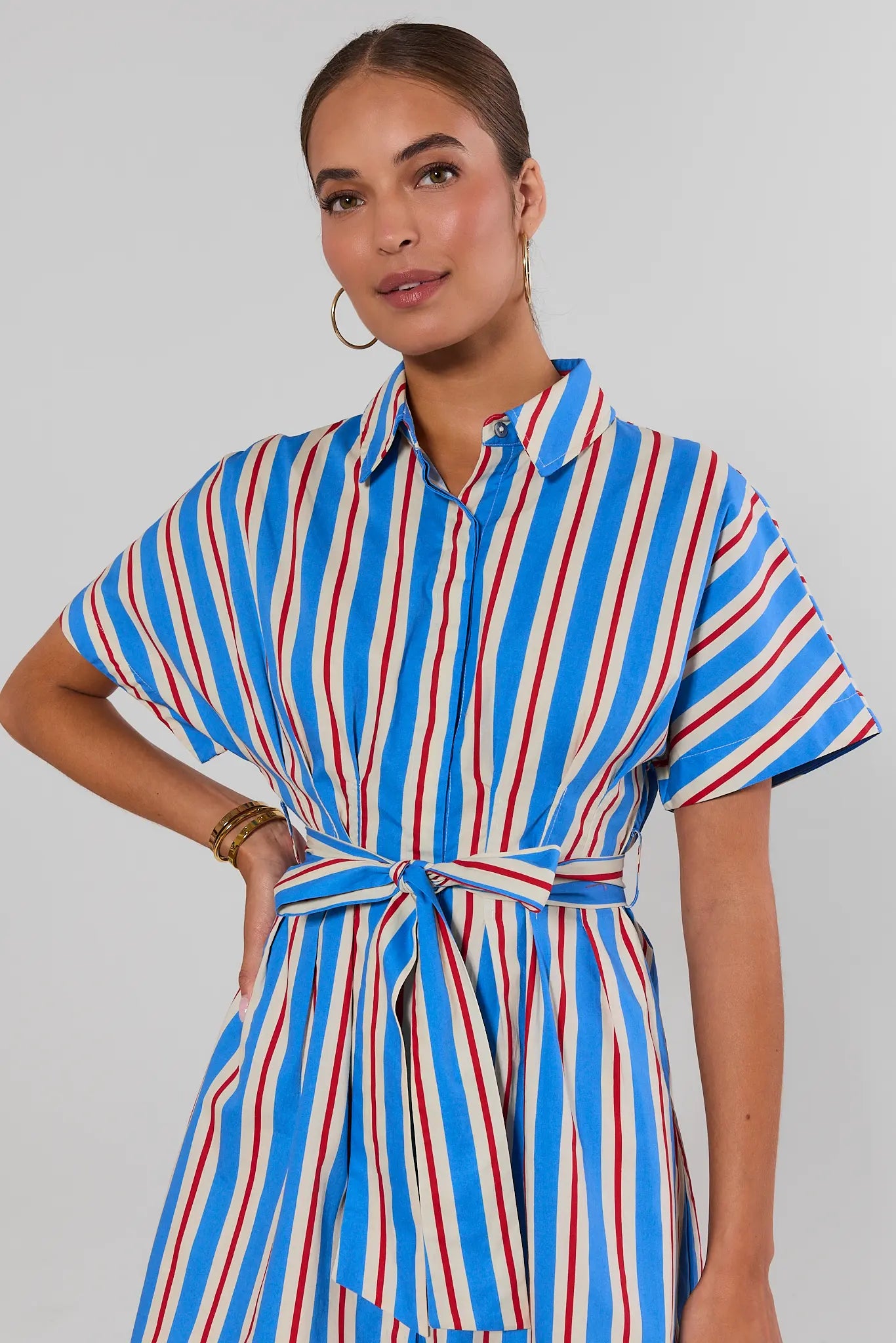 close up Woman wearing a blue, red, and white striped dress against a plain background