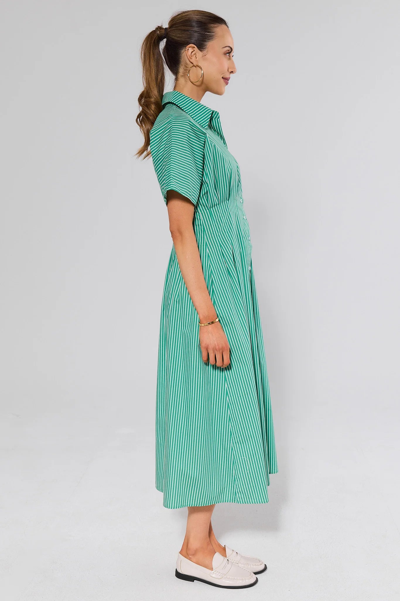 side shot Woman wearing a green checkered dress on a white background