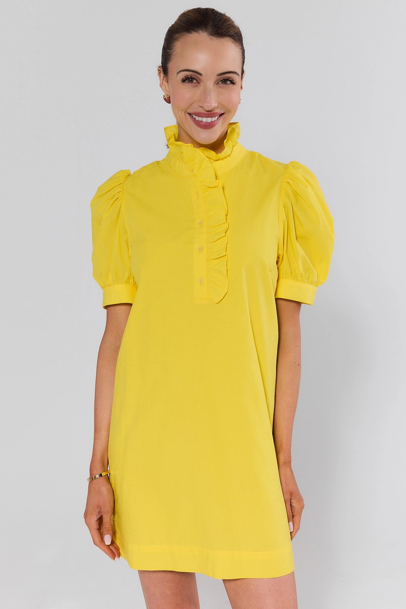 Woman wearing a yellow dress with puff sleeves against a white background