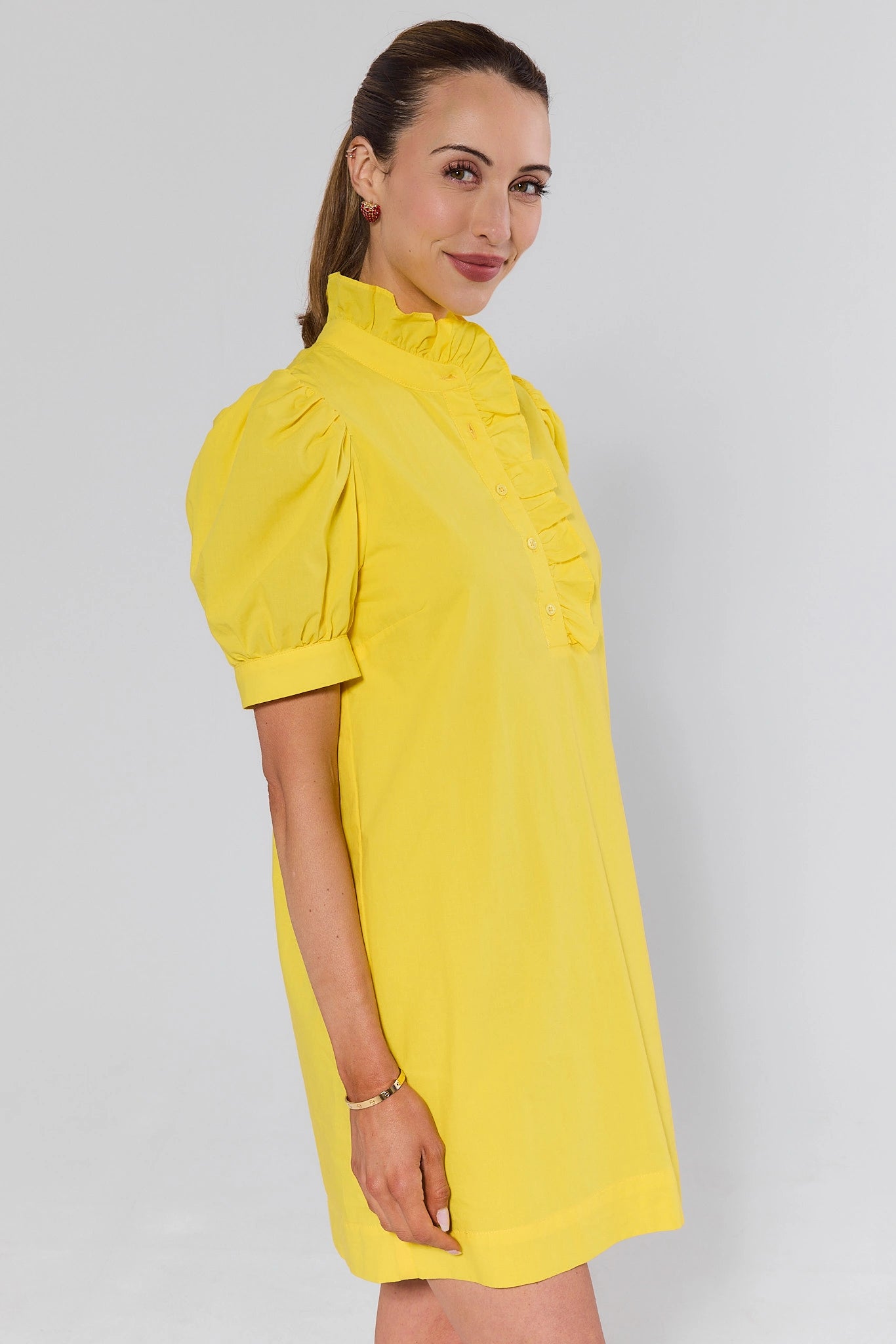 side shot Woman wearing a yellow dress against a plain background