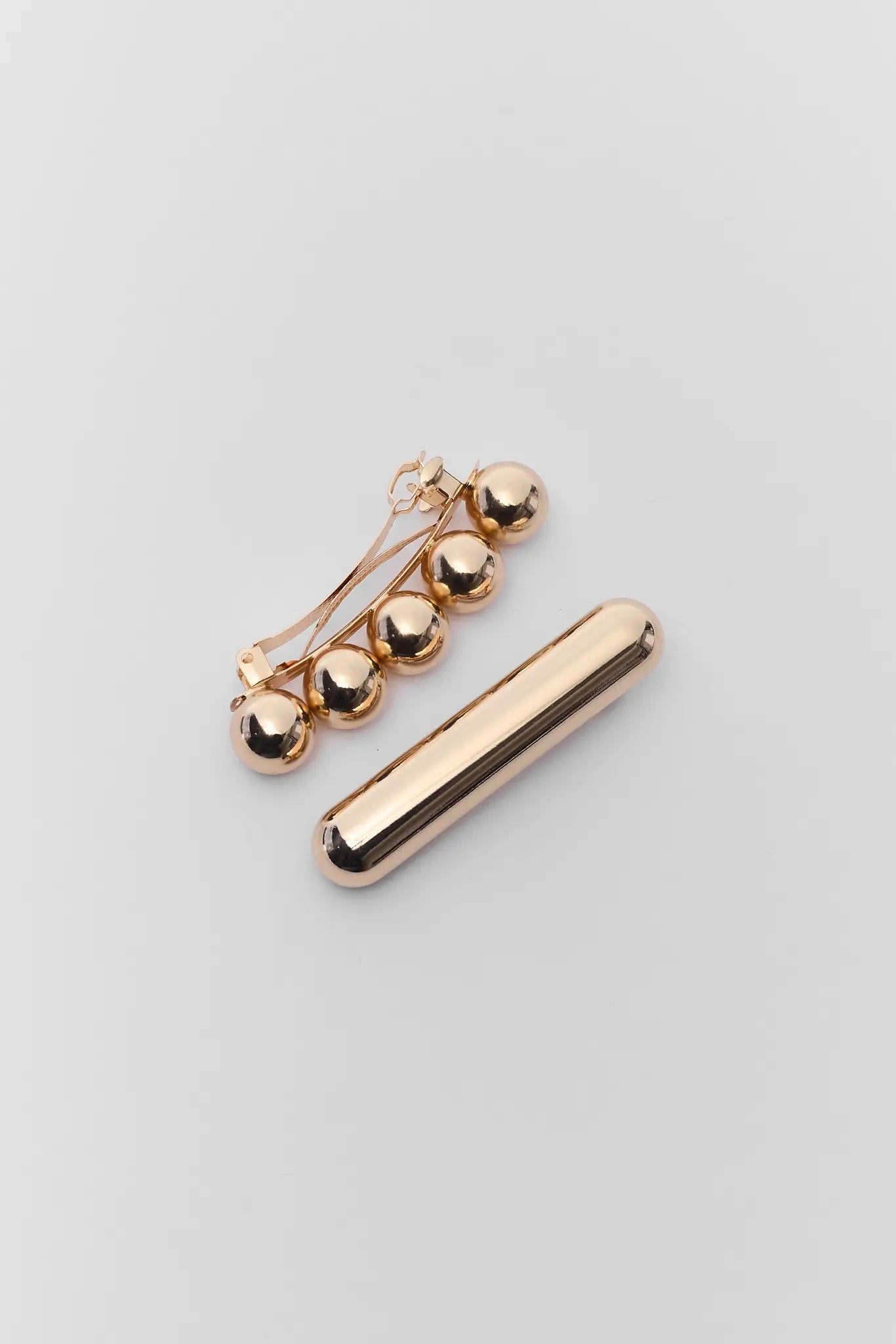 Gold bar and spherical earring on a light gray background