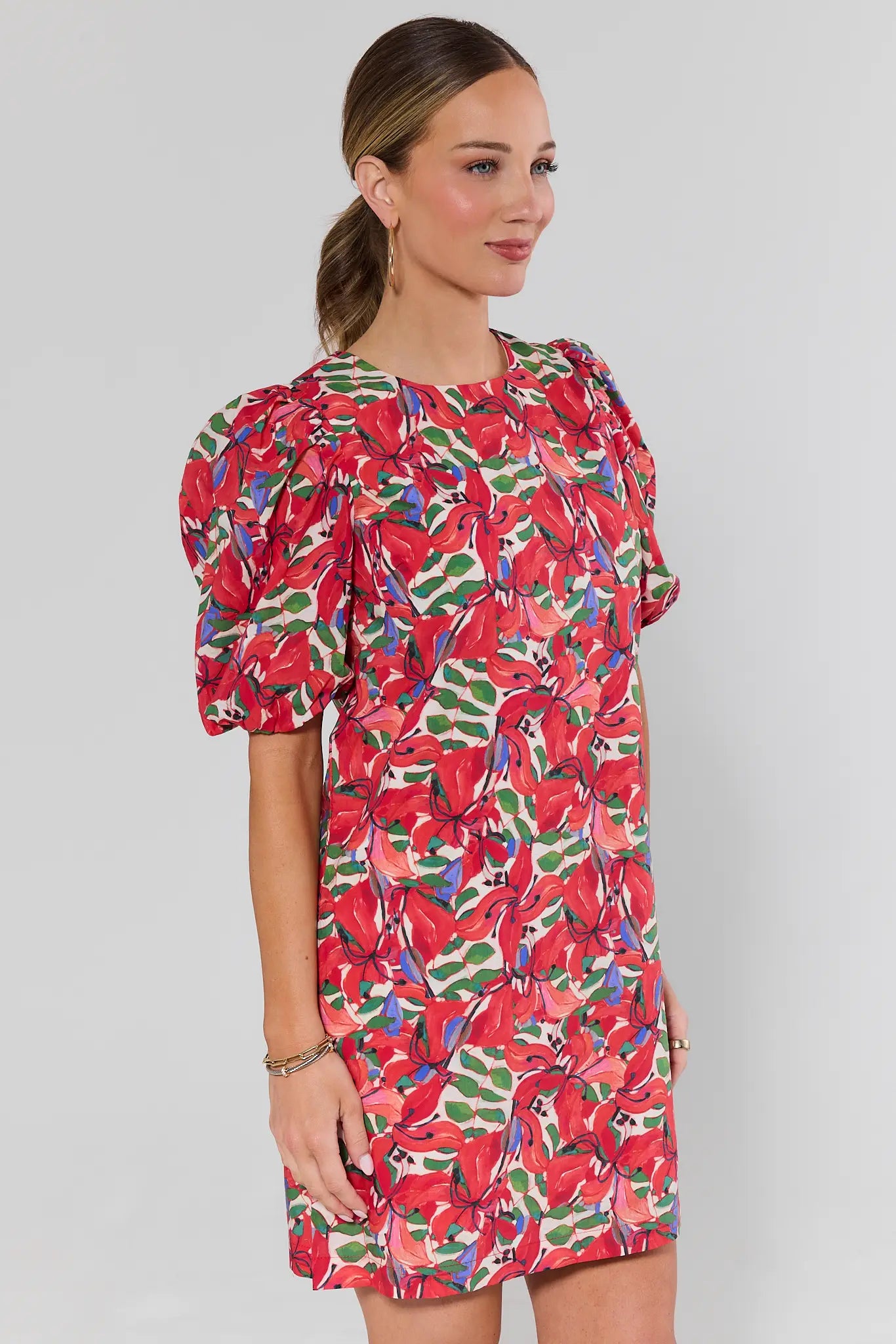 side shot Woman wearing a colorful floral dress against a plain background
