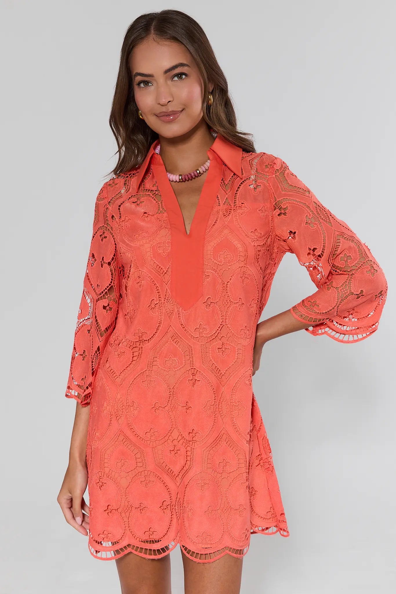 Woman wearing a coral lace dress on a gray background