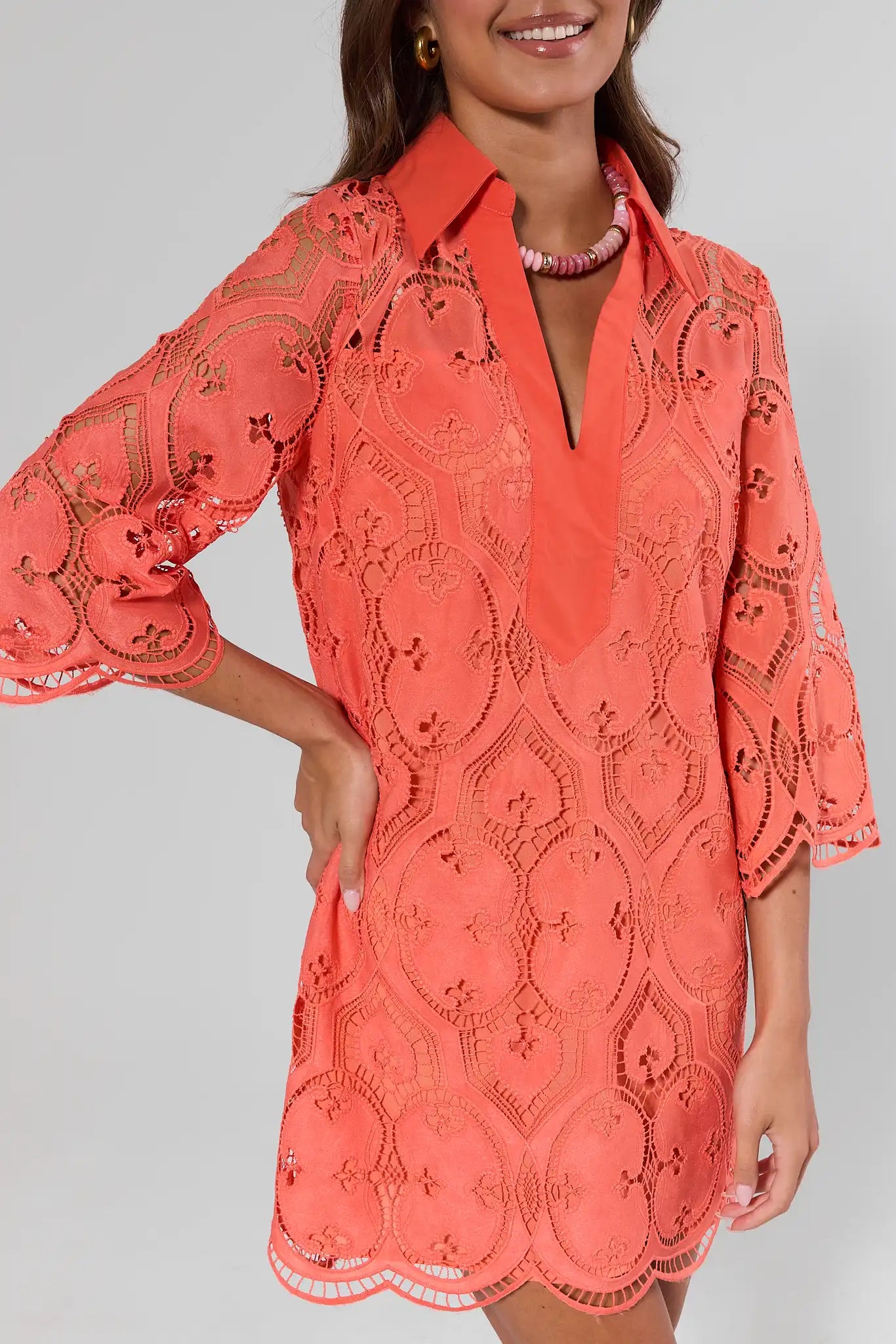close up Coral lace dress worn by a model on a plain background