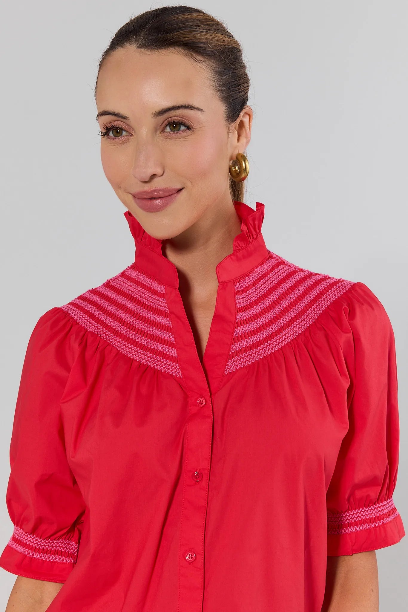 close up Woman wearing a red blouse with white embroidery on a gray background