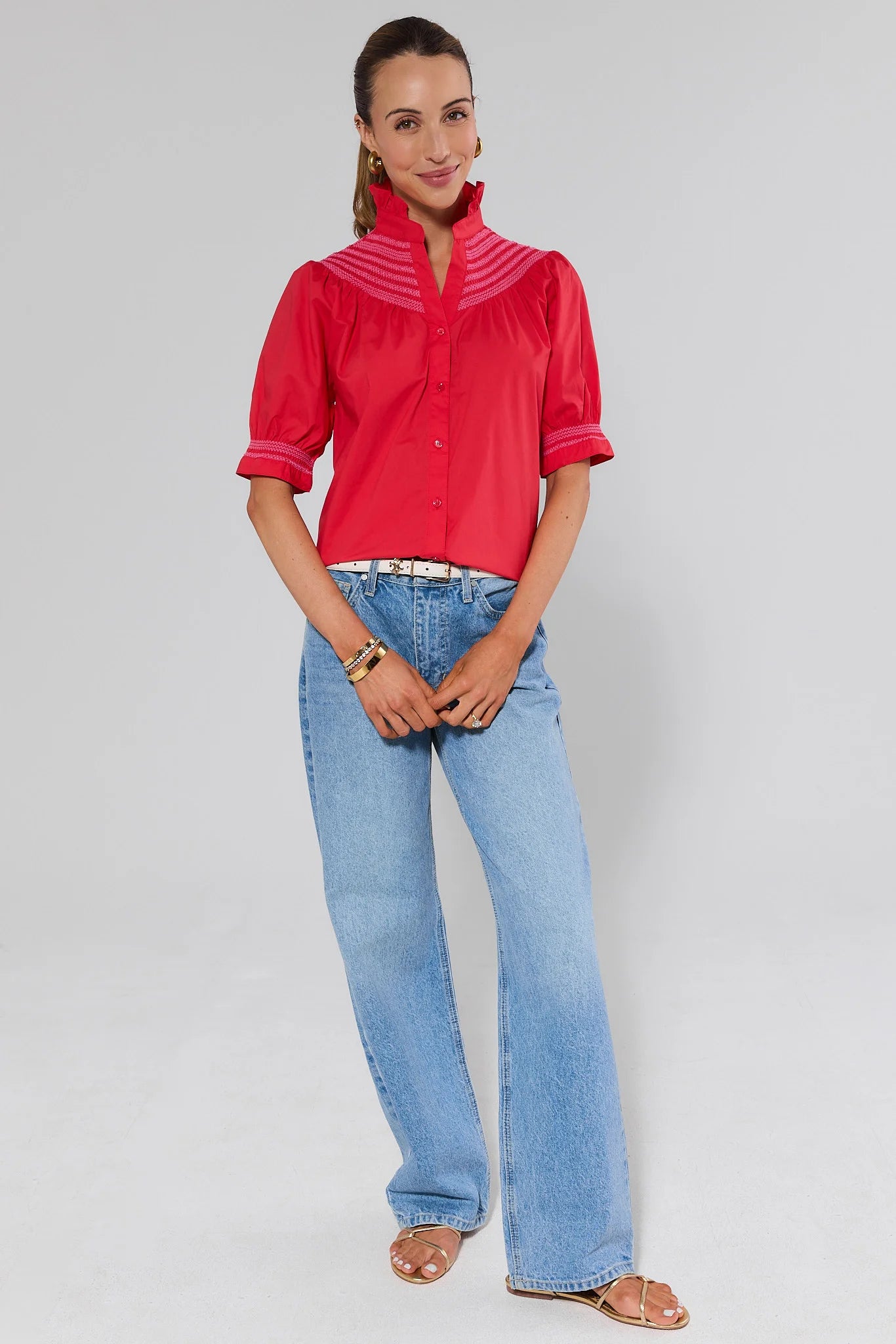 Woman wearing a red blouse and blue jeans on a plain background