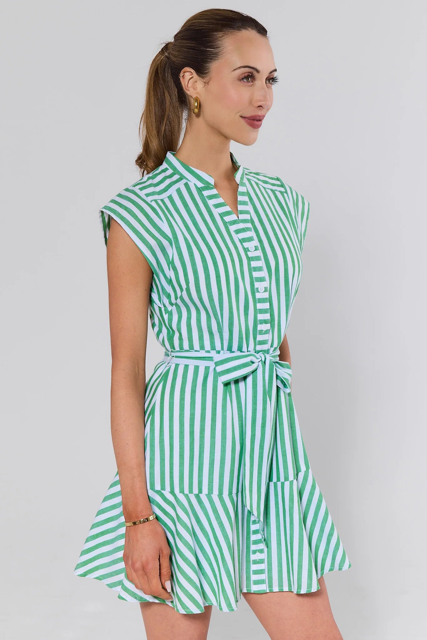 side shot Woman wearing a green and white striped dress against a plain background