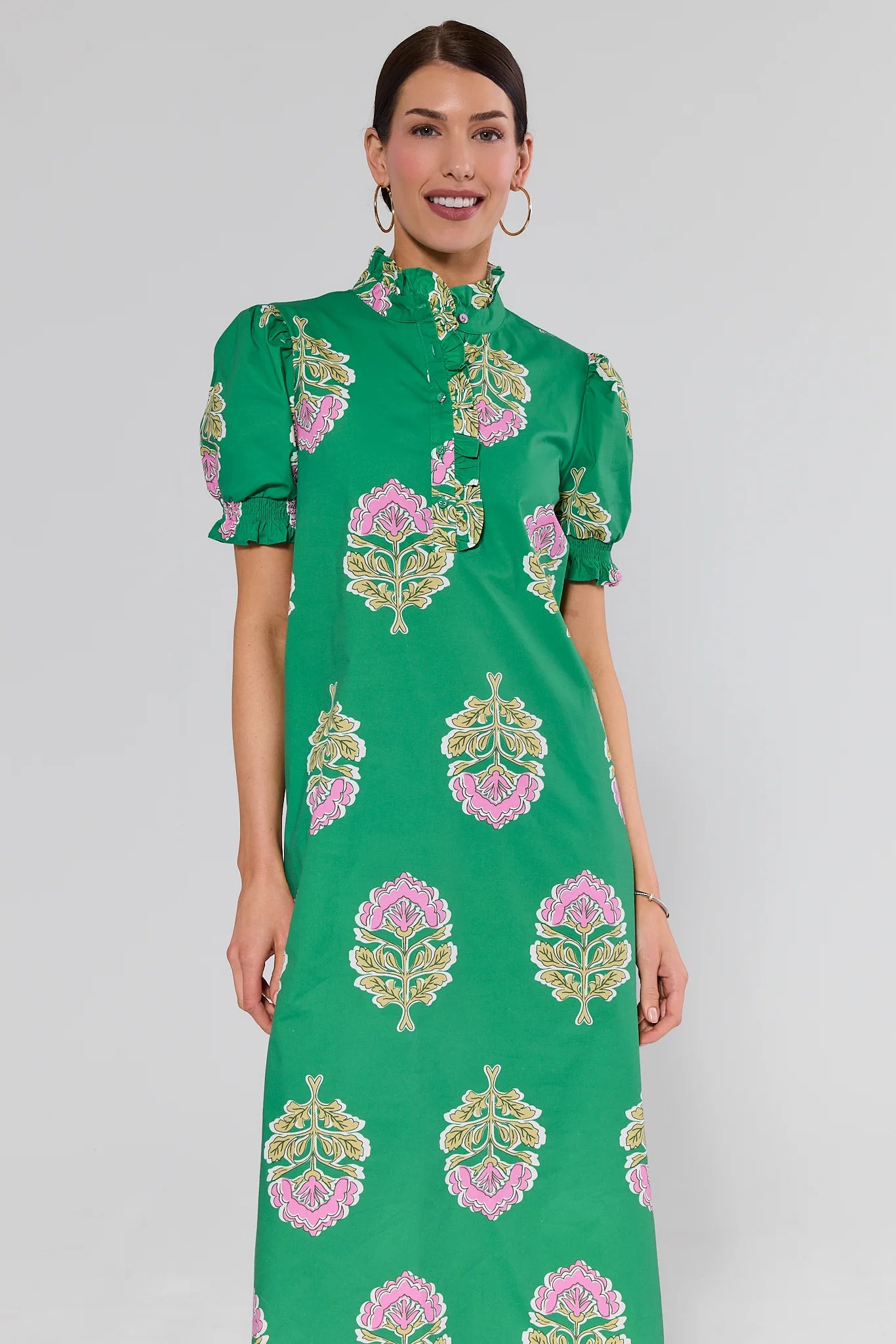 Woman wearing a green dress with floral patterns on a gray background
